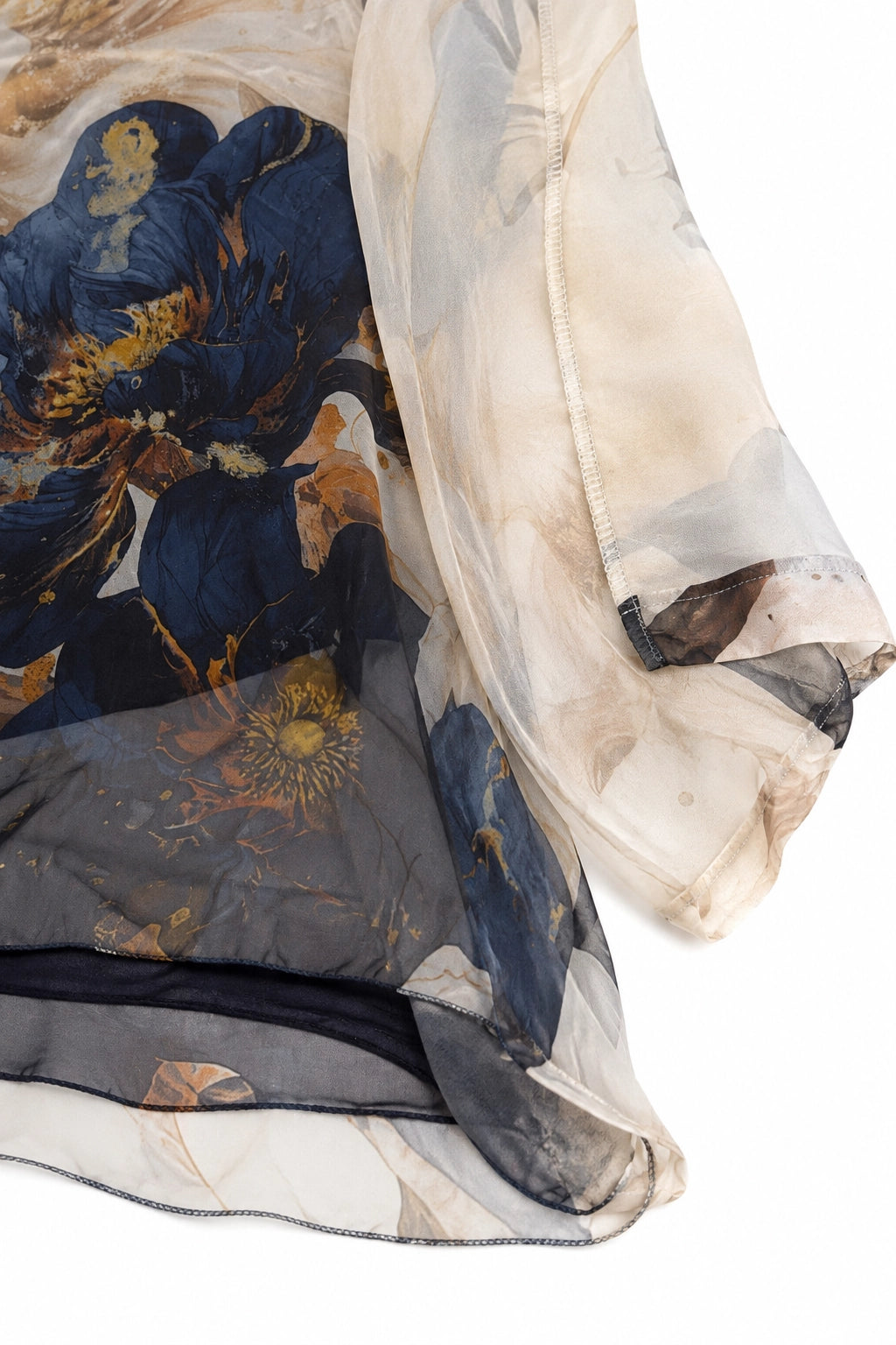 A close-up of a sheer, lightweight fabric garment or scarf with an abstract floral print in navy blue, beige, brown, and gold tones, shown against a plain white background.