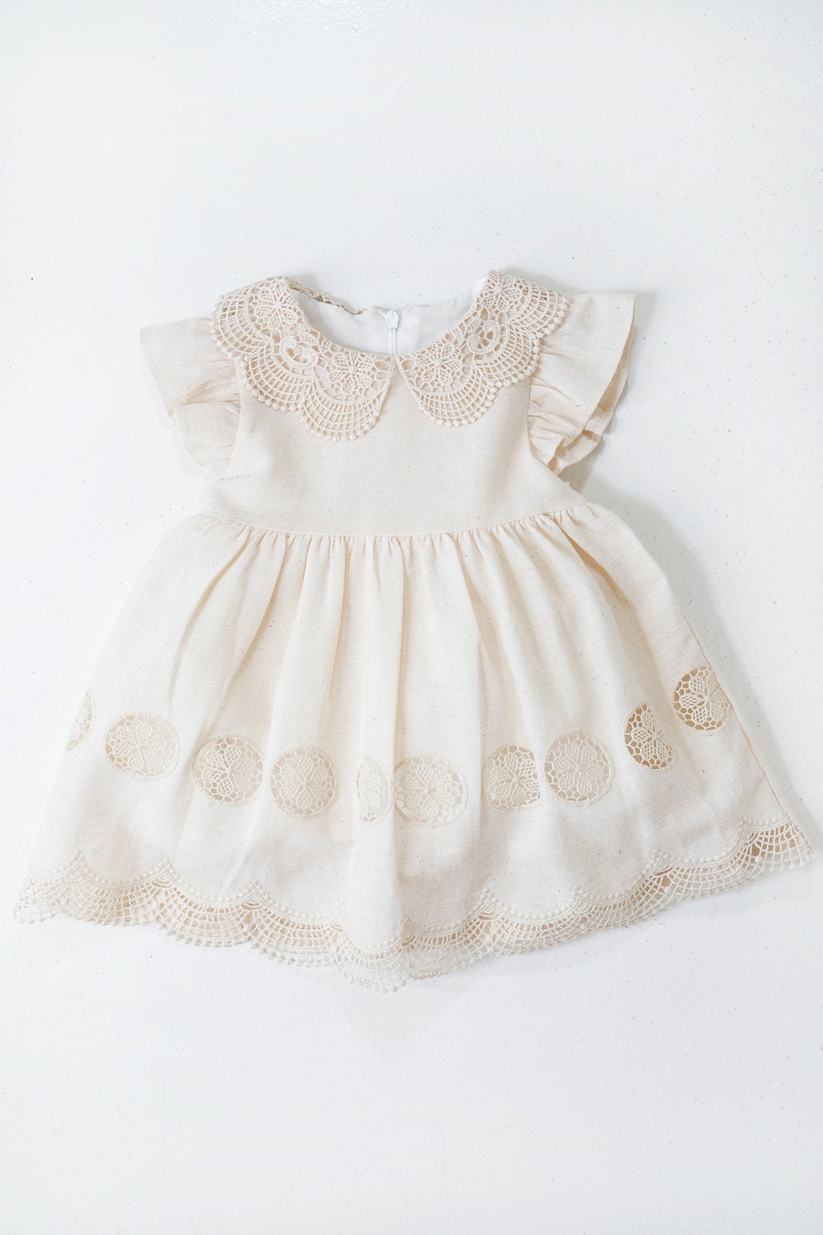 Beige baby dress with floral embroidery on a white background