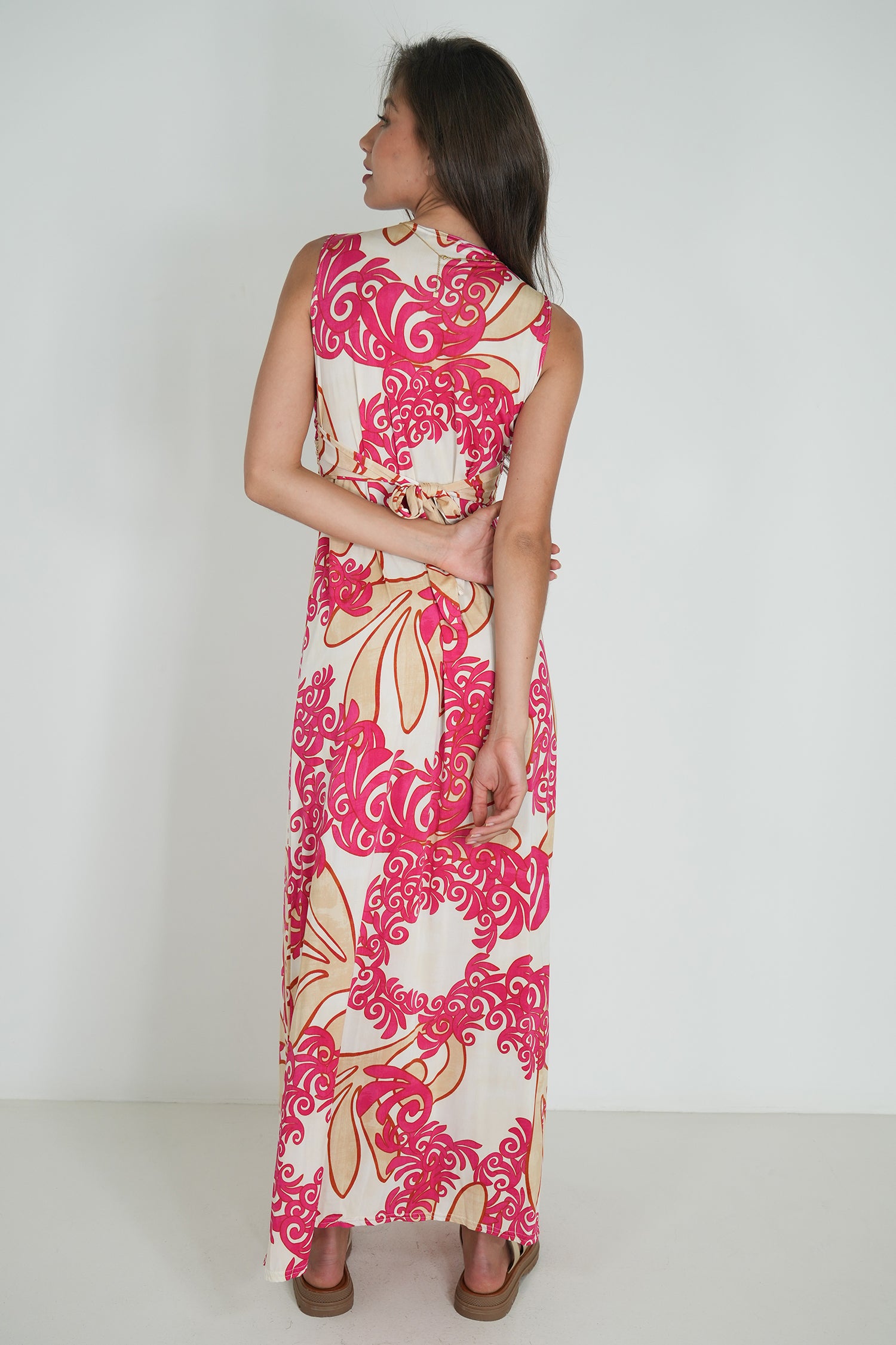 Woman wearing a pink and white floral dress against a plain background