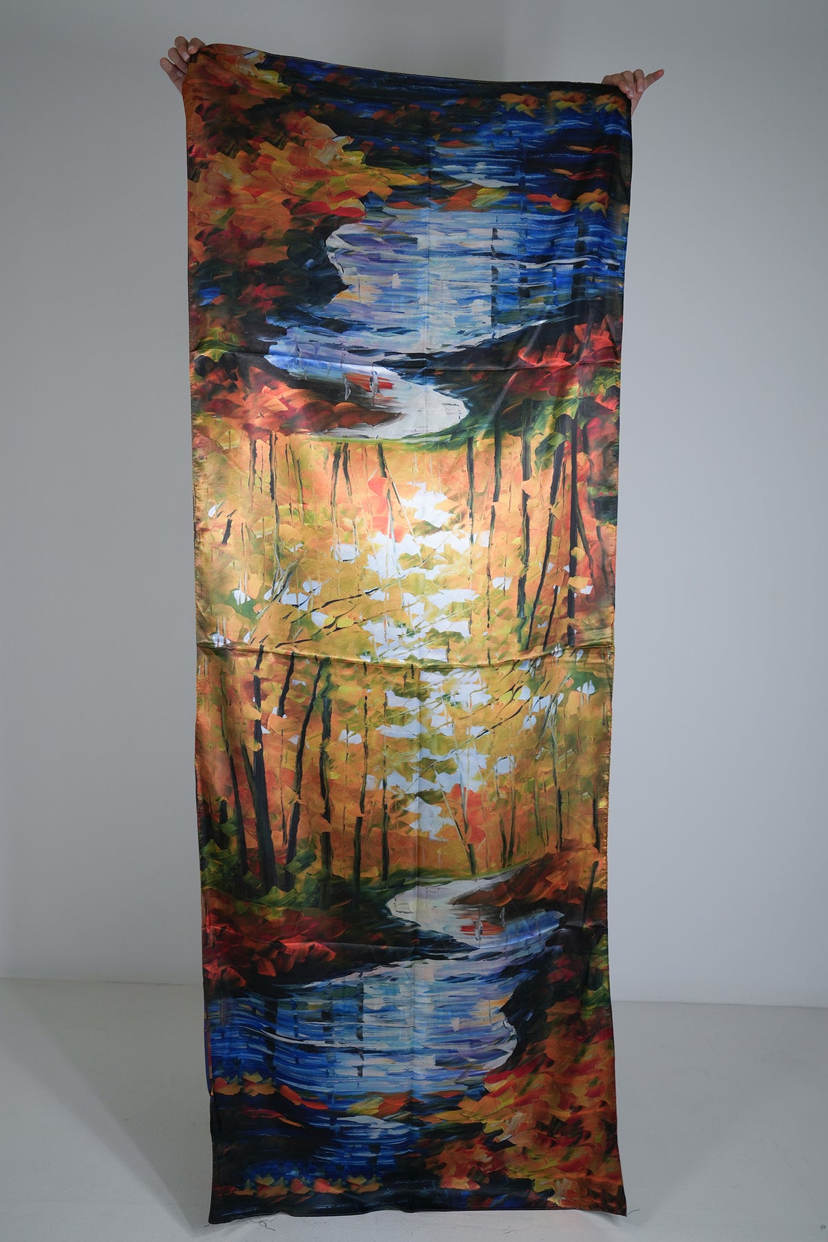 Colourful fabric with a nature-themed design held up against a plain background