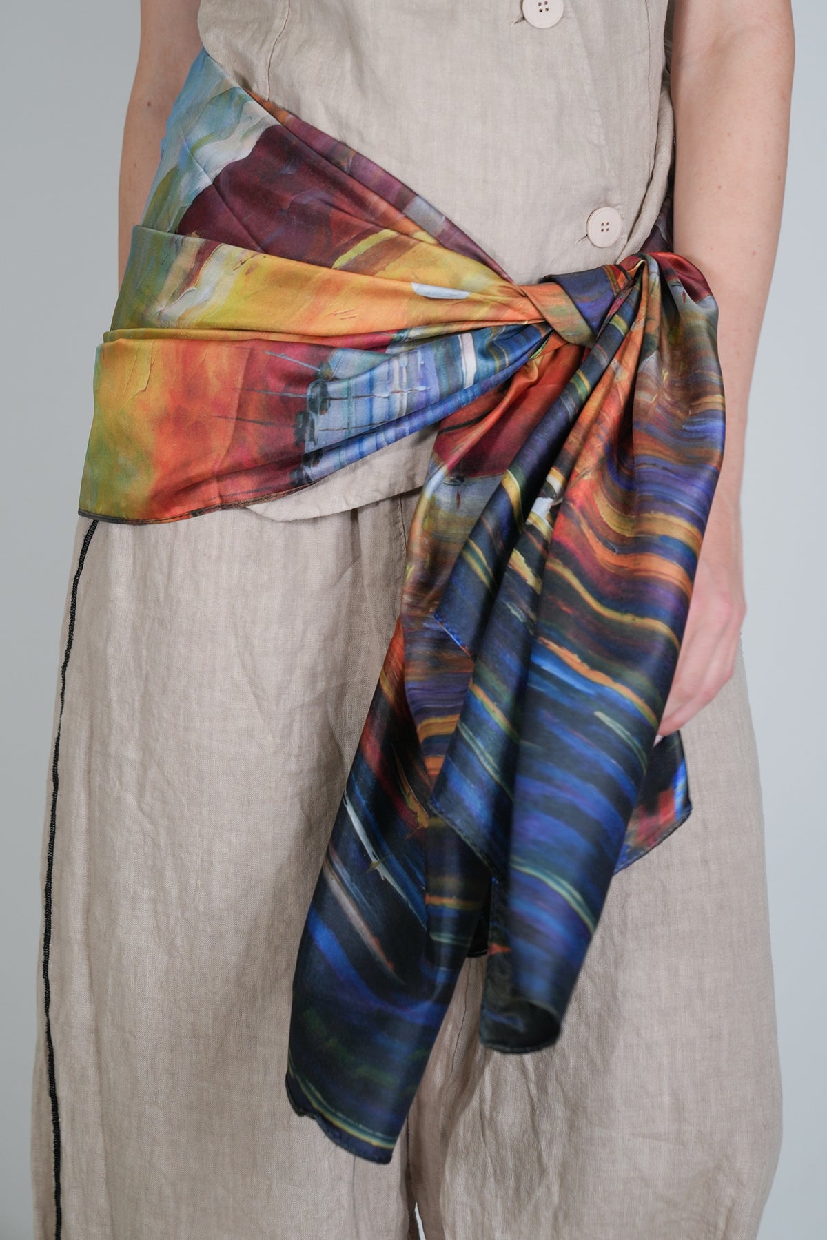 Person wearing a colorful scarf with abstract patterns on a plain background
