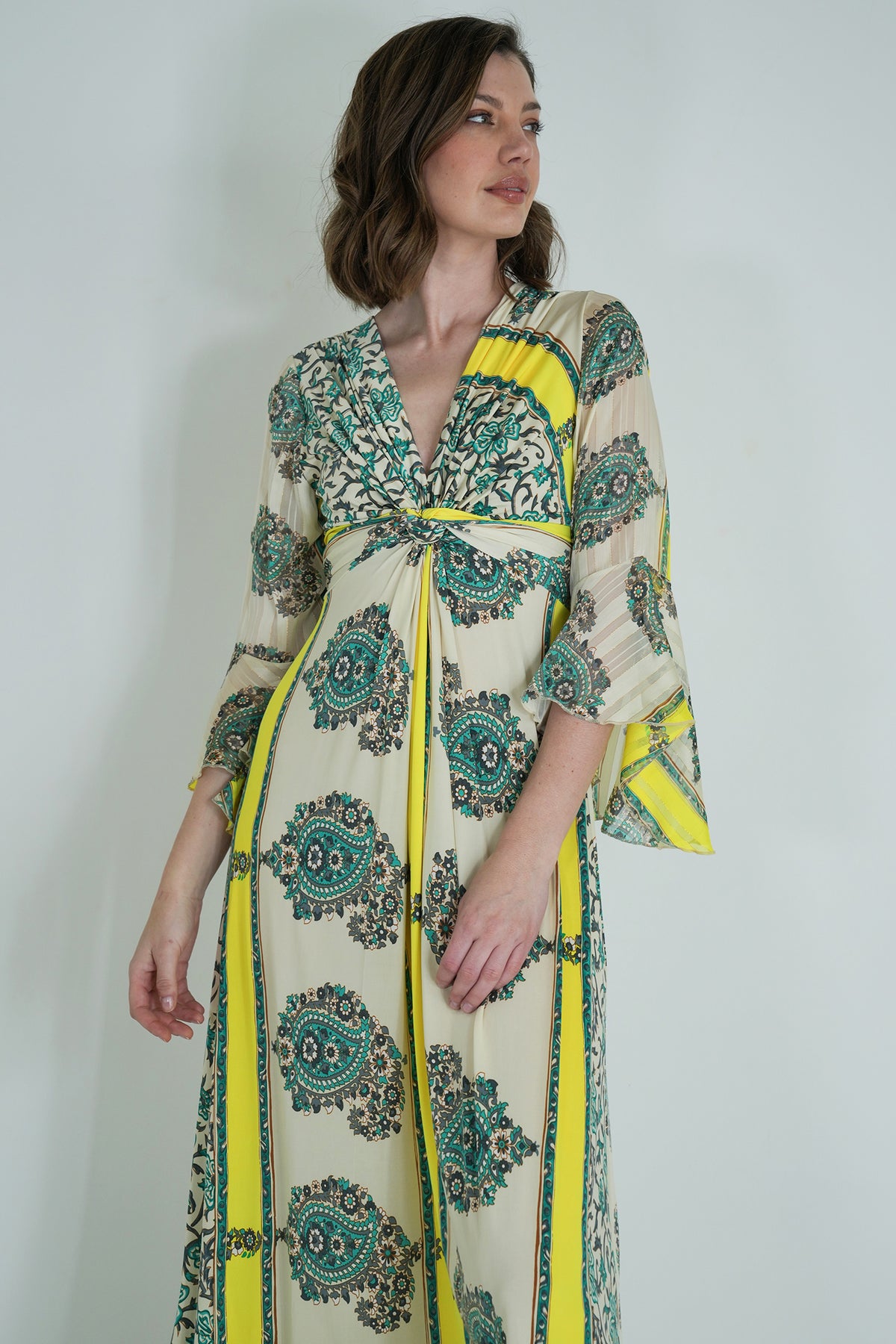 Woman wearing a patterned dress with yellow accents against a plain background