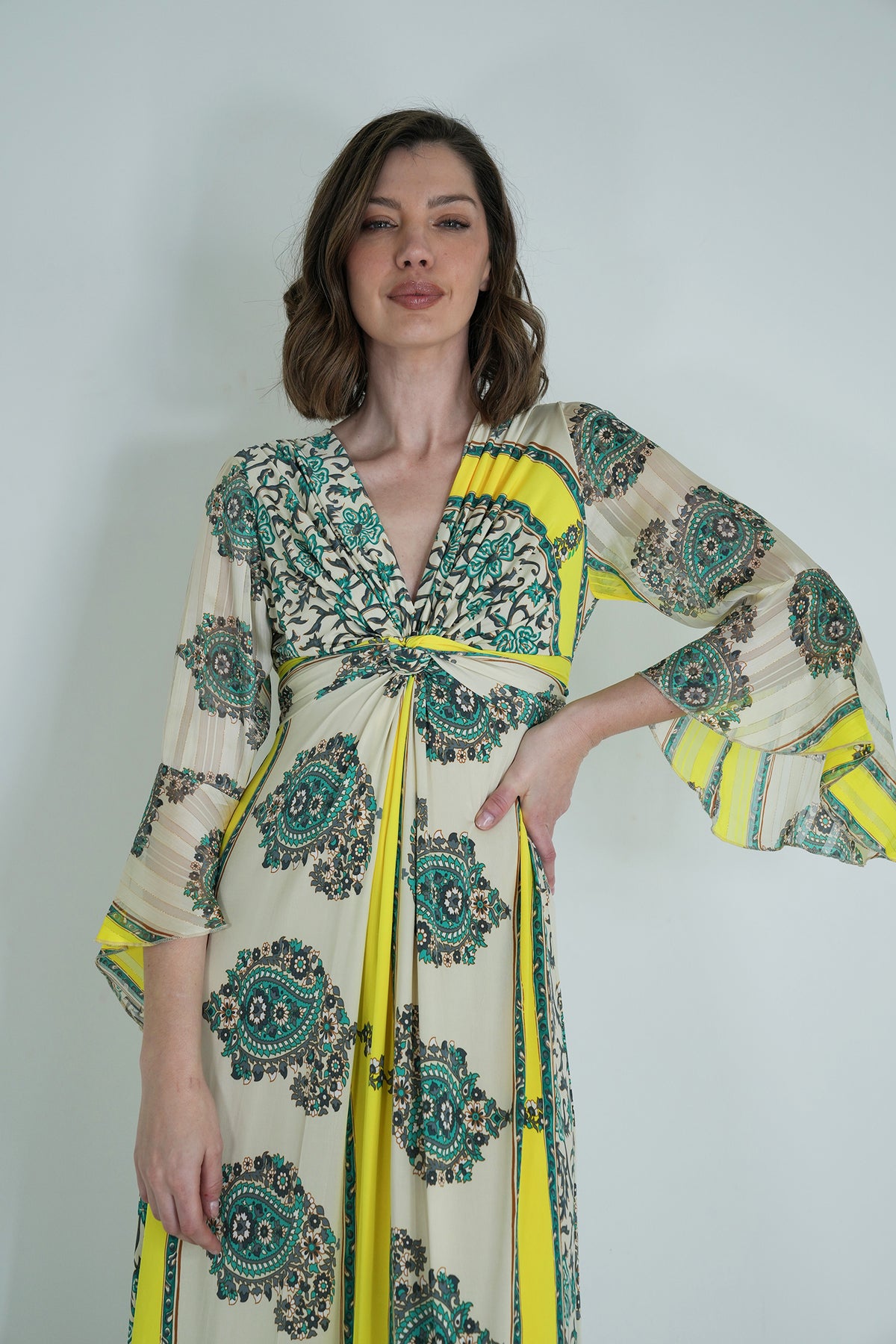Woman wearing a patterned dress with yellow accents on a plain background