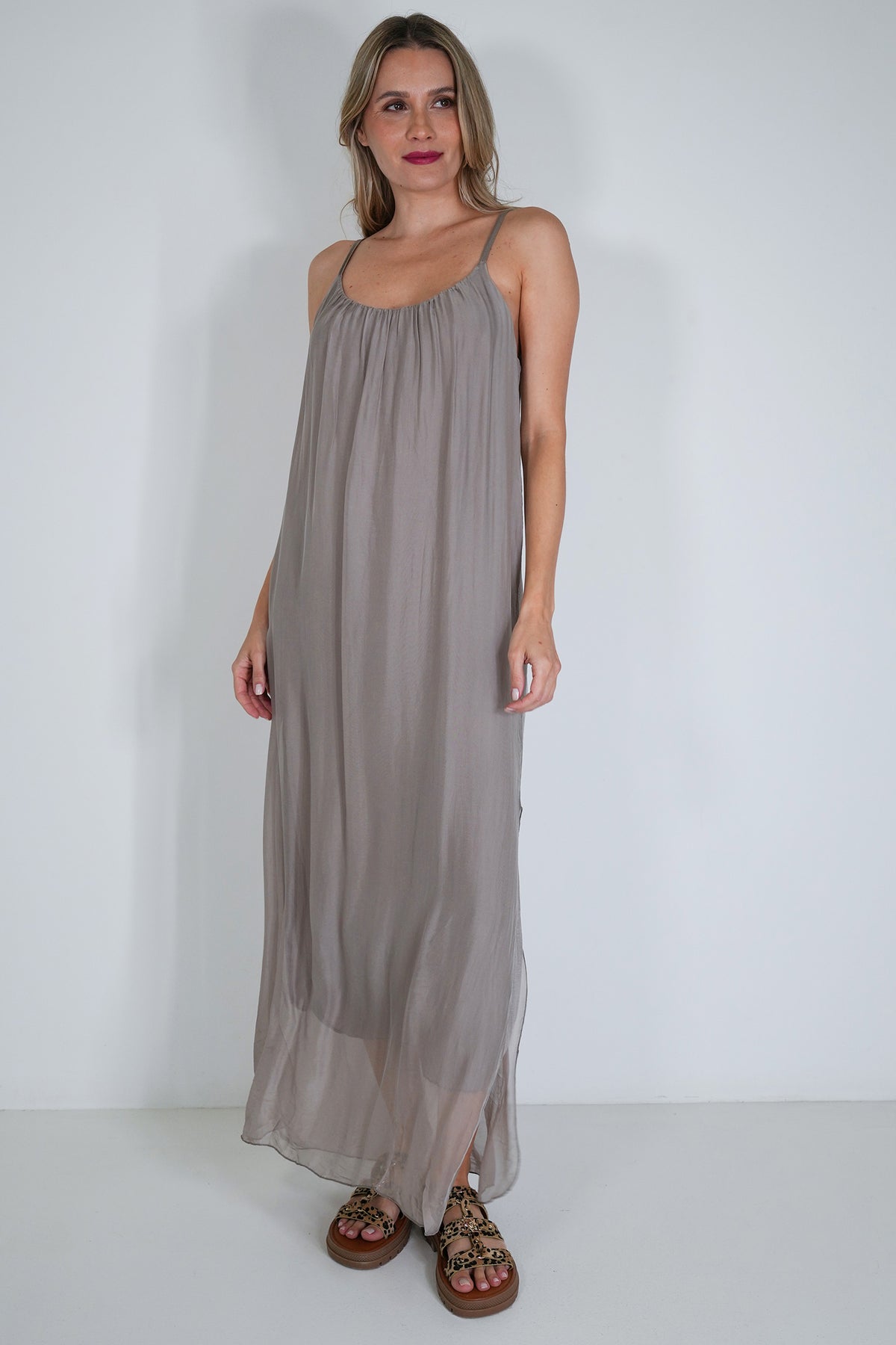 Woman wearing a long gray dress against a white background