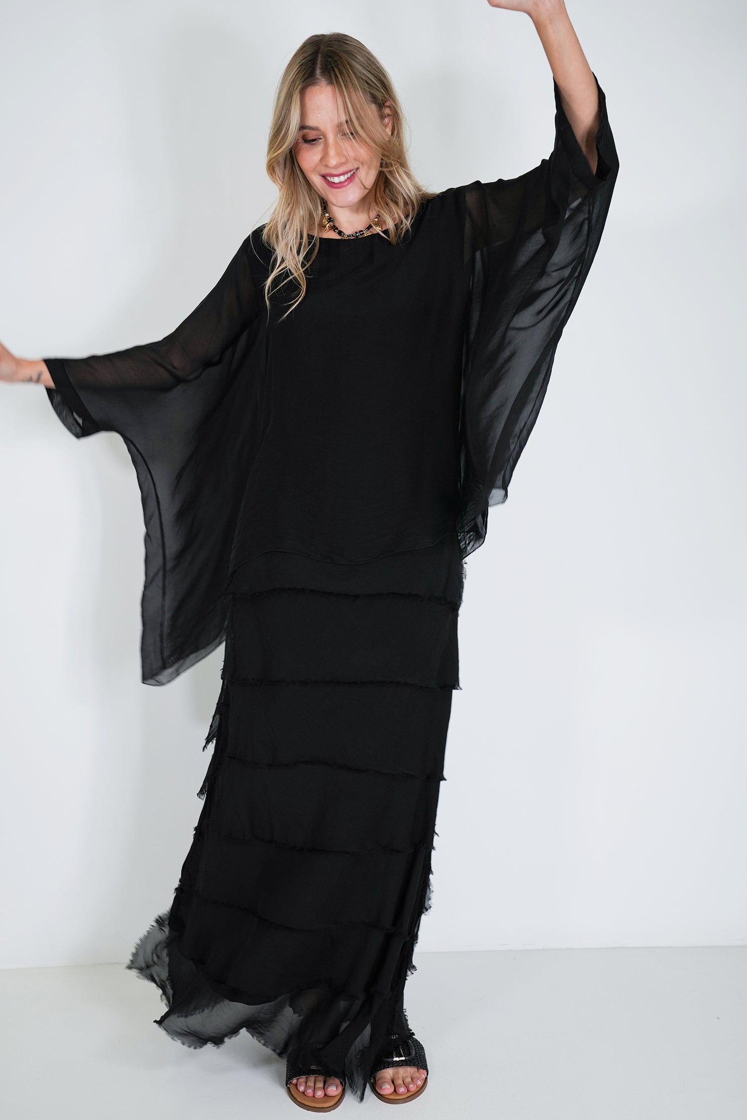 Woman wearing a black layered dress against a white background