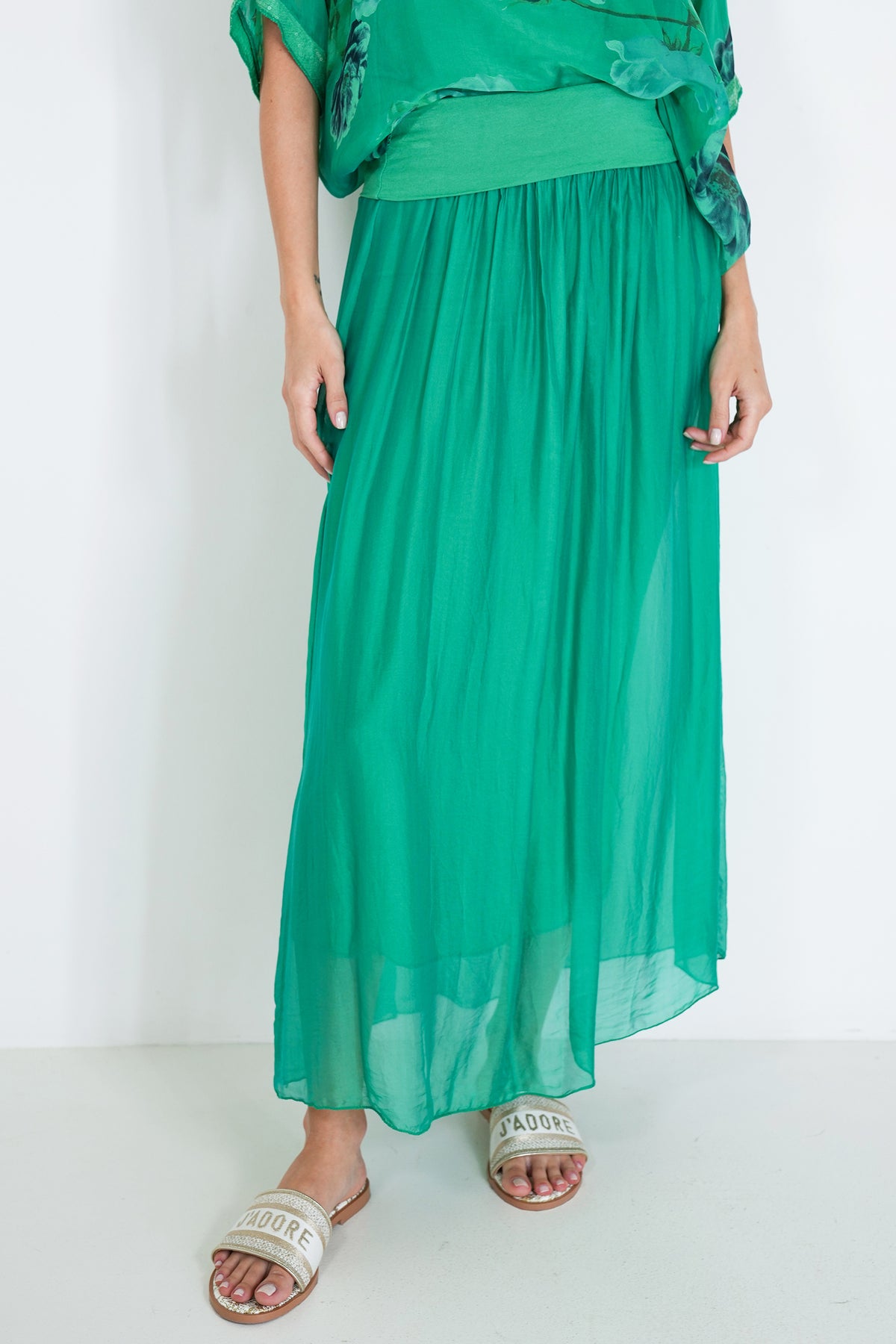 Person wearing a green outfit with a long skirt on a white background