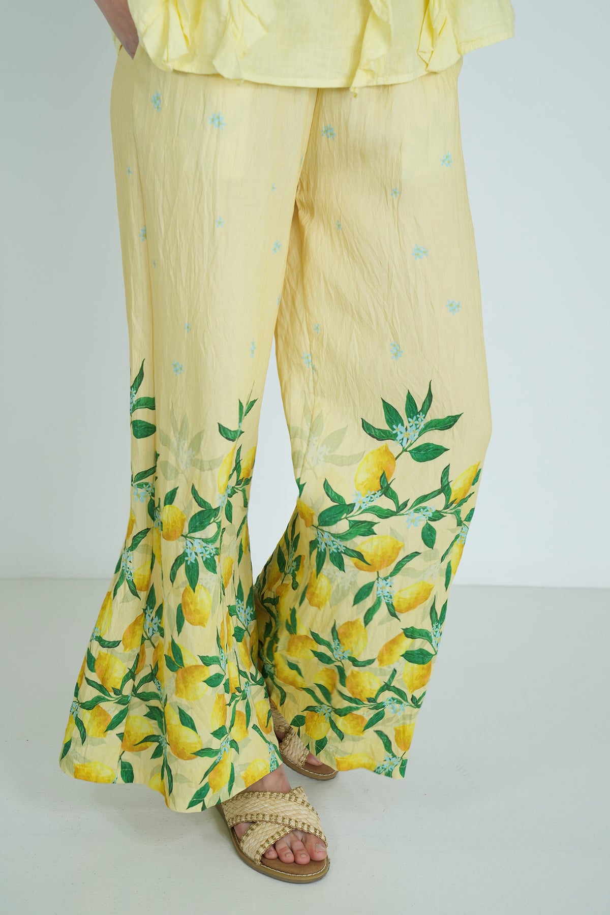 Yellow outfit with lemon print pants on a plain background