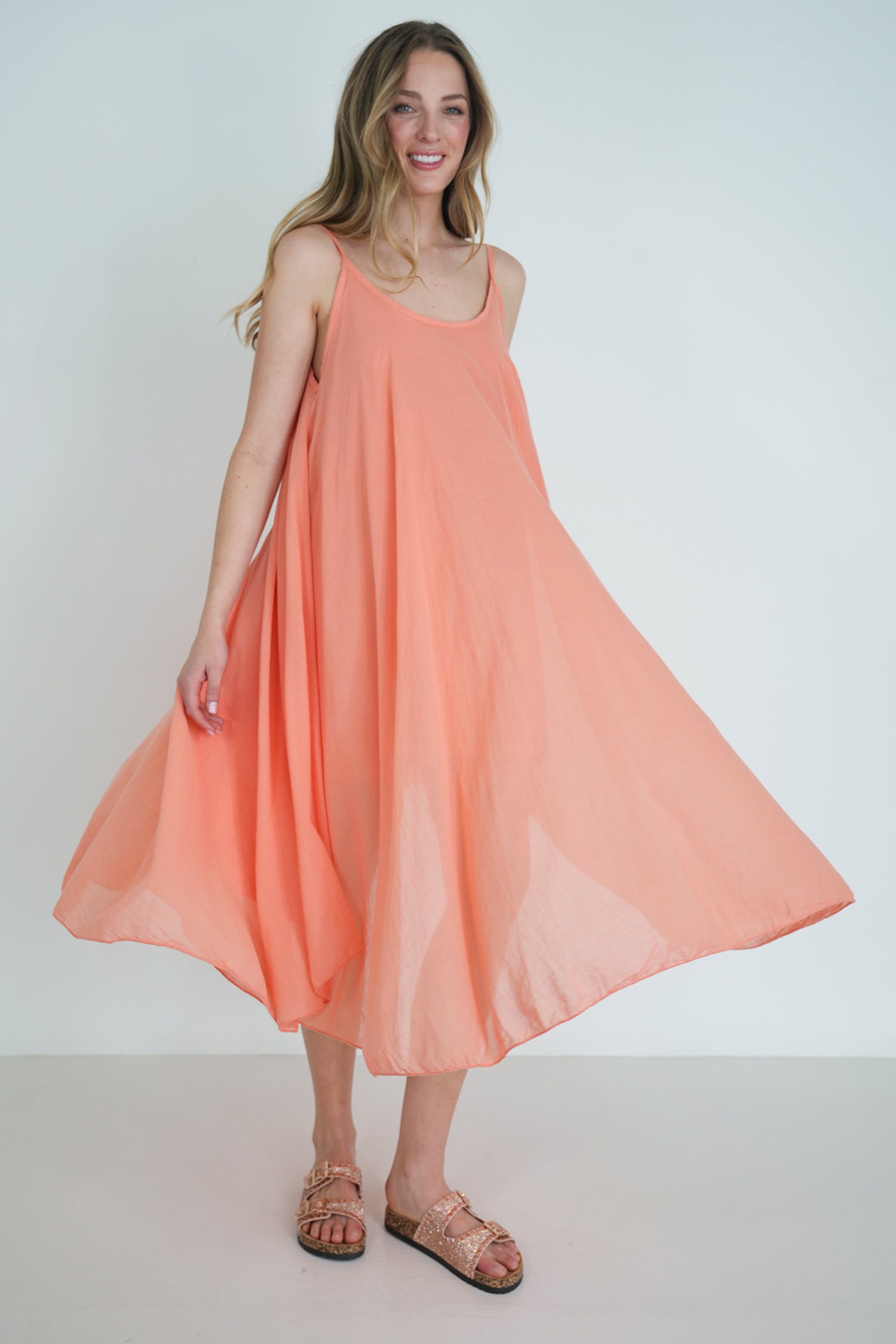 Woman wearing a peach-colored dress against a white background