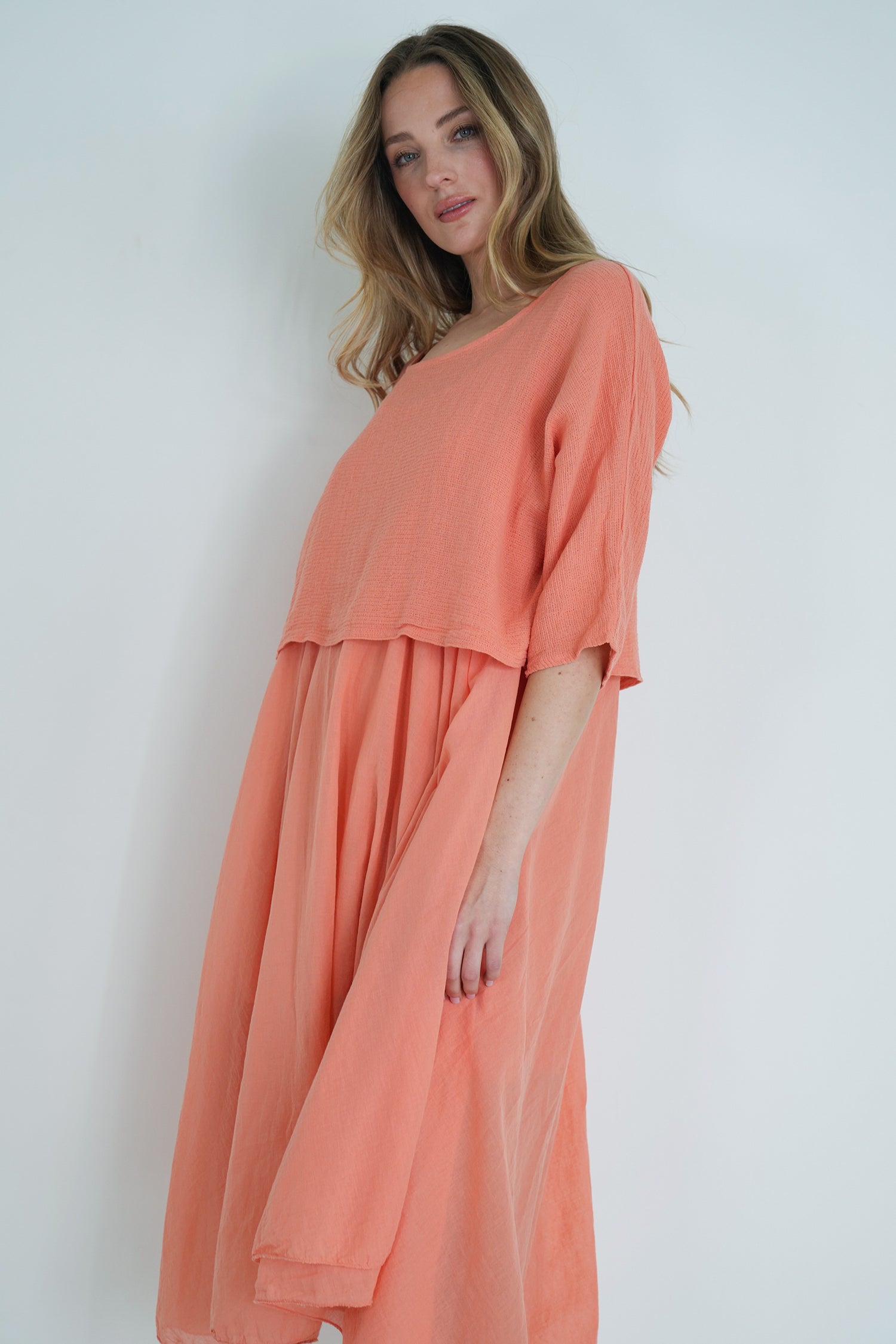 Woman wearing a peach-colored dress against a white background