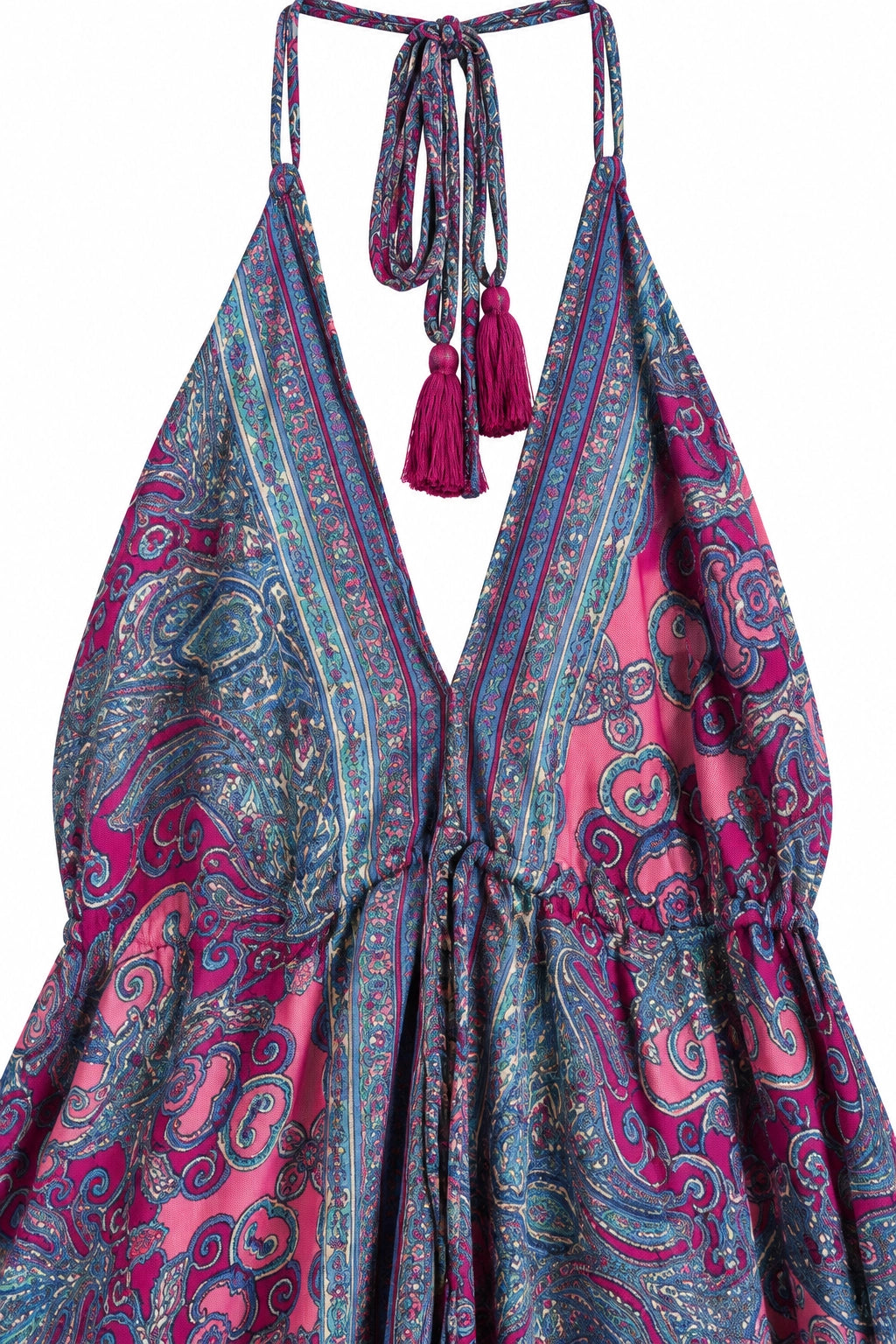 A close-up of a halter-neck dress with a deep V-neckline, tie straps, and tassel accents, featuring a vibrant paisley pattern in pink, teal, and blue.