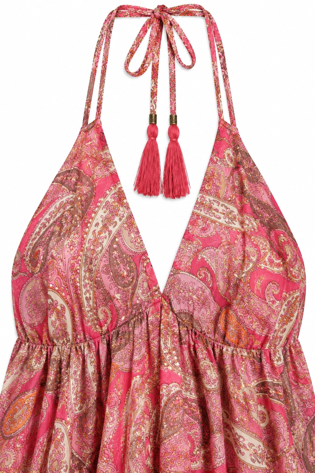 A close-up of a halter-neck dress with a vibrant pink and red paisley pattern, featuring tie straps with tassel accents.