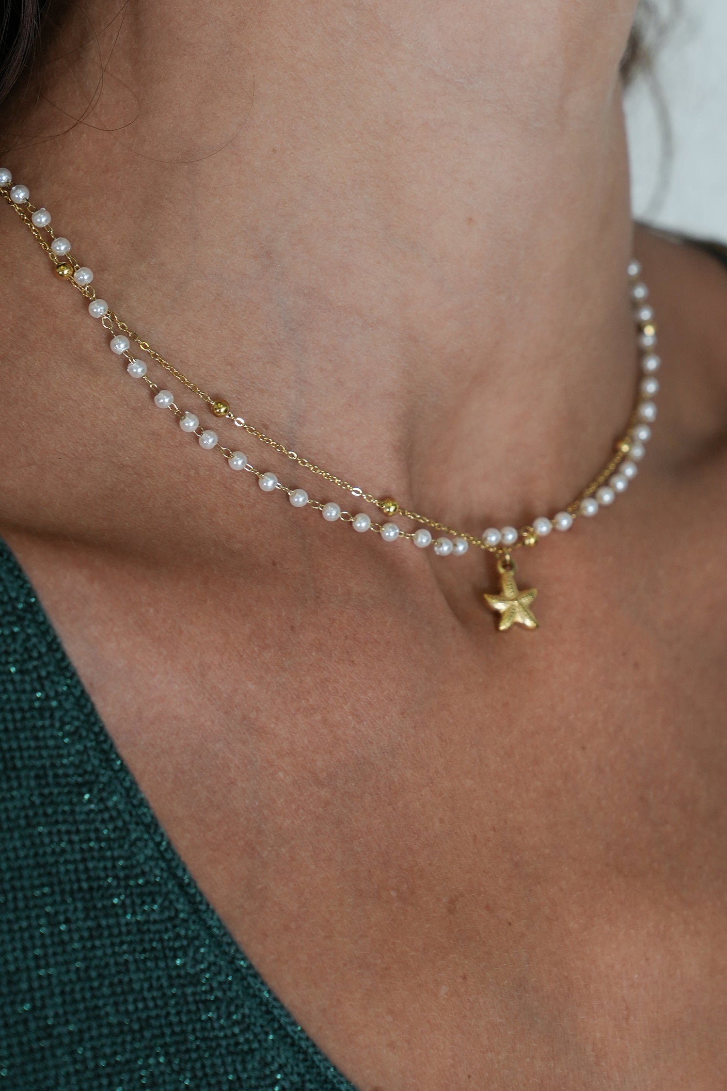 Pearl necklace with a gold star pendant worn by a person