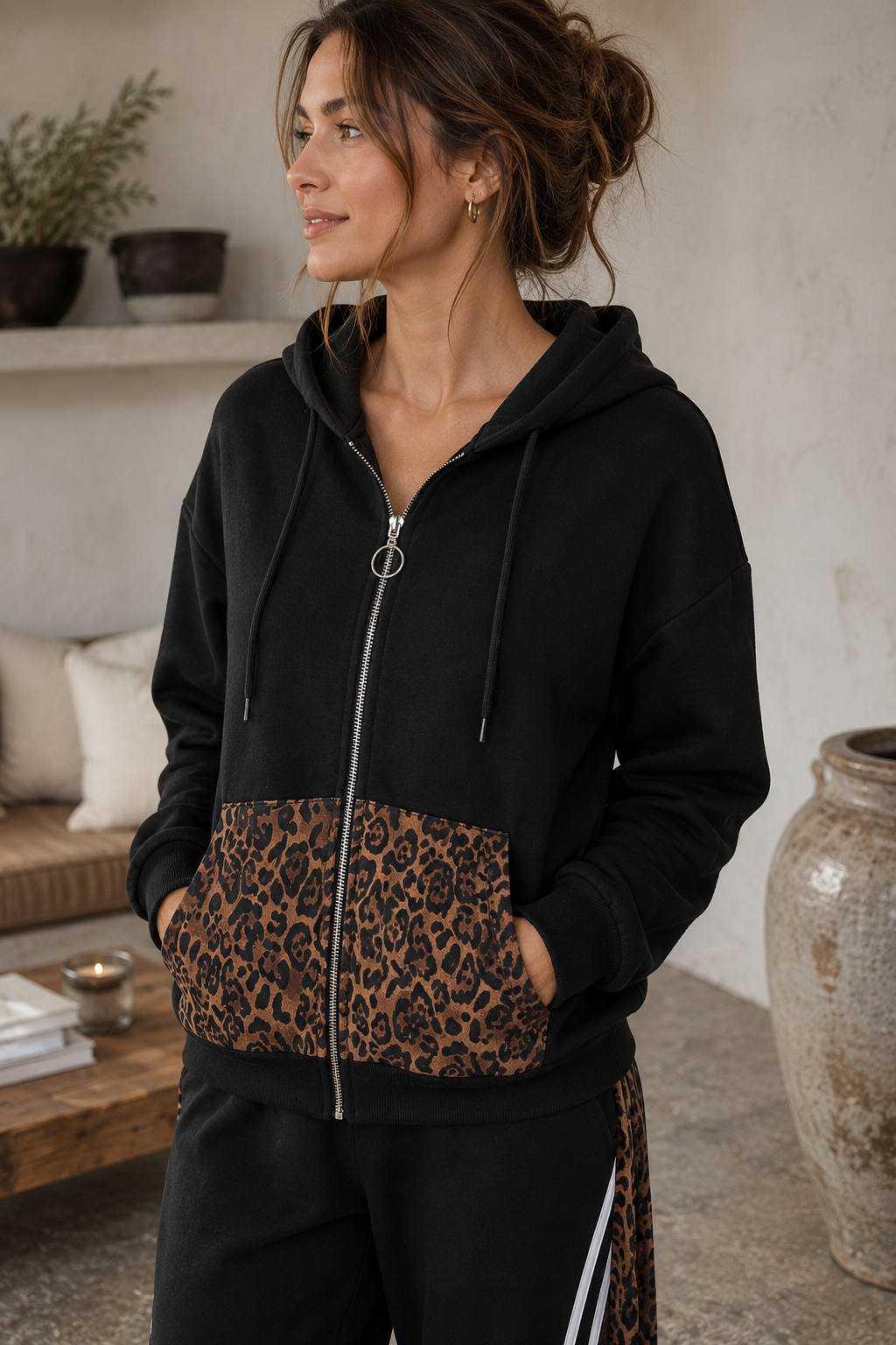 Woman wearing a black hoodie with leopard print pocket in an indoor setting