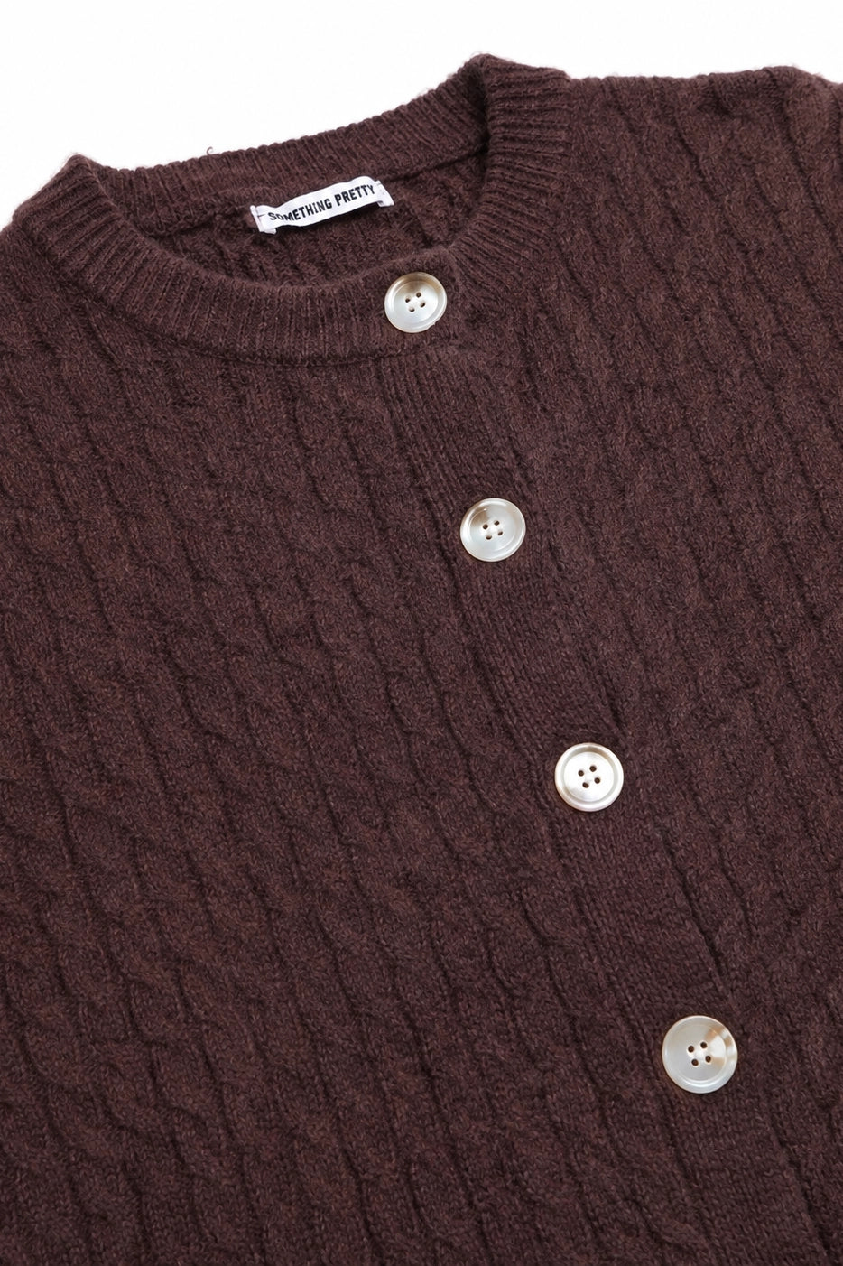 Close-up of a brown textured sweater with buttons, featuring the brand 'American Pretty'.