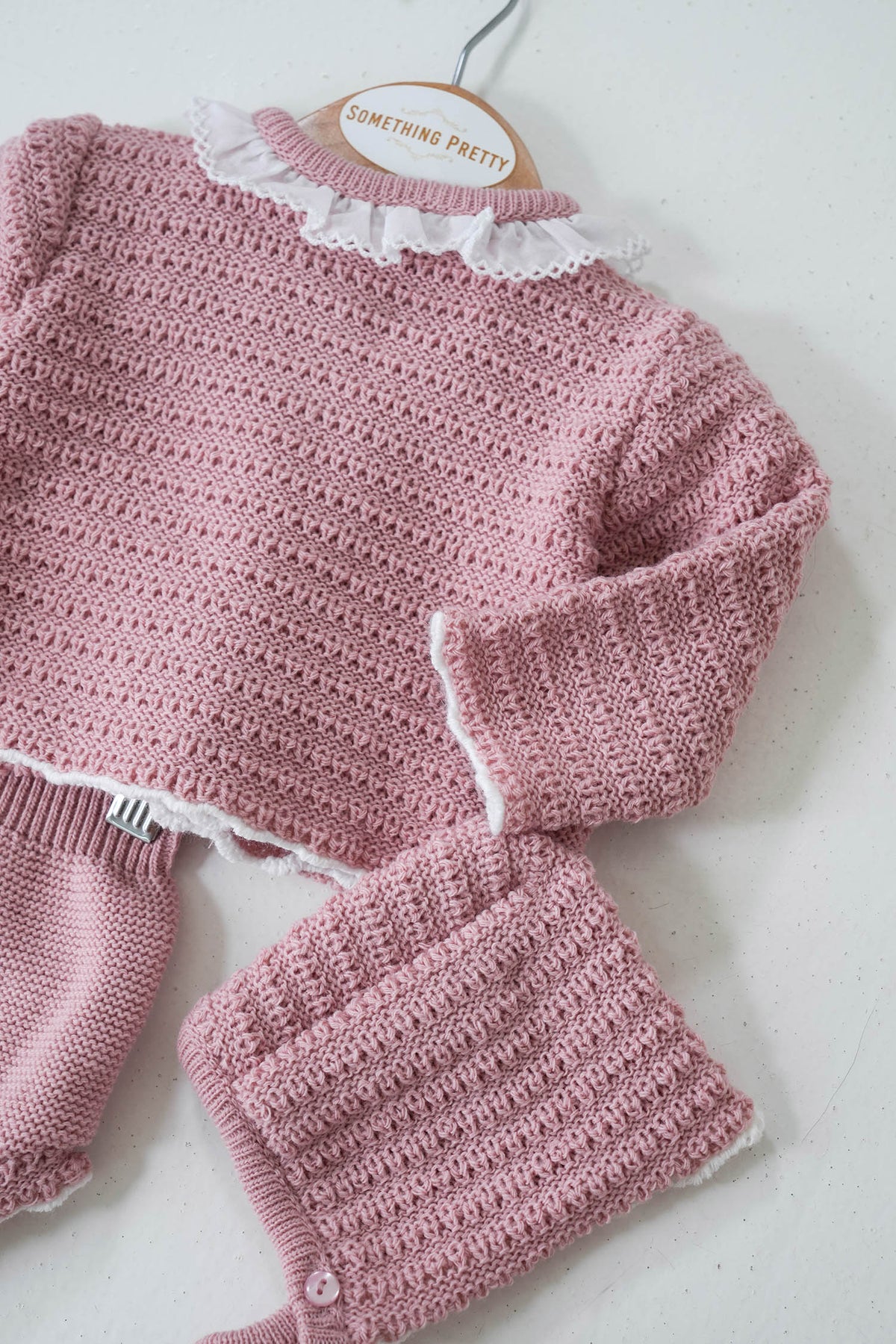 A dusty pink knit set for a girl, consisting of a long-sleeved top with a round neckline and matching pants, displayed on a mannequin.