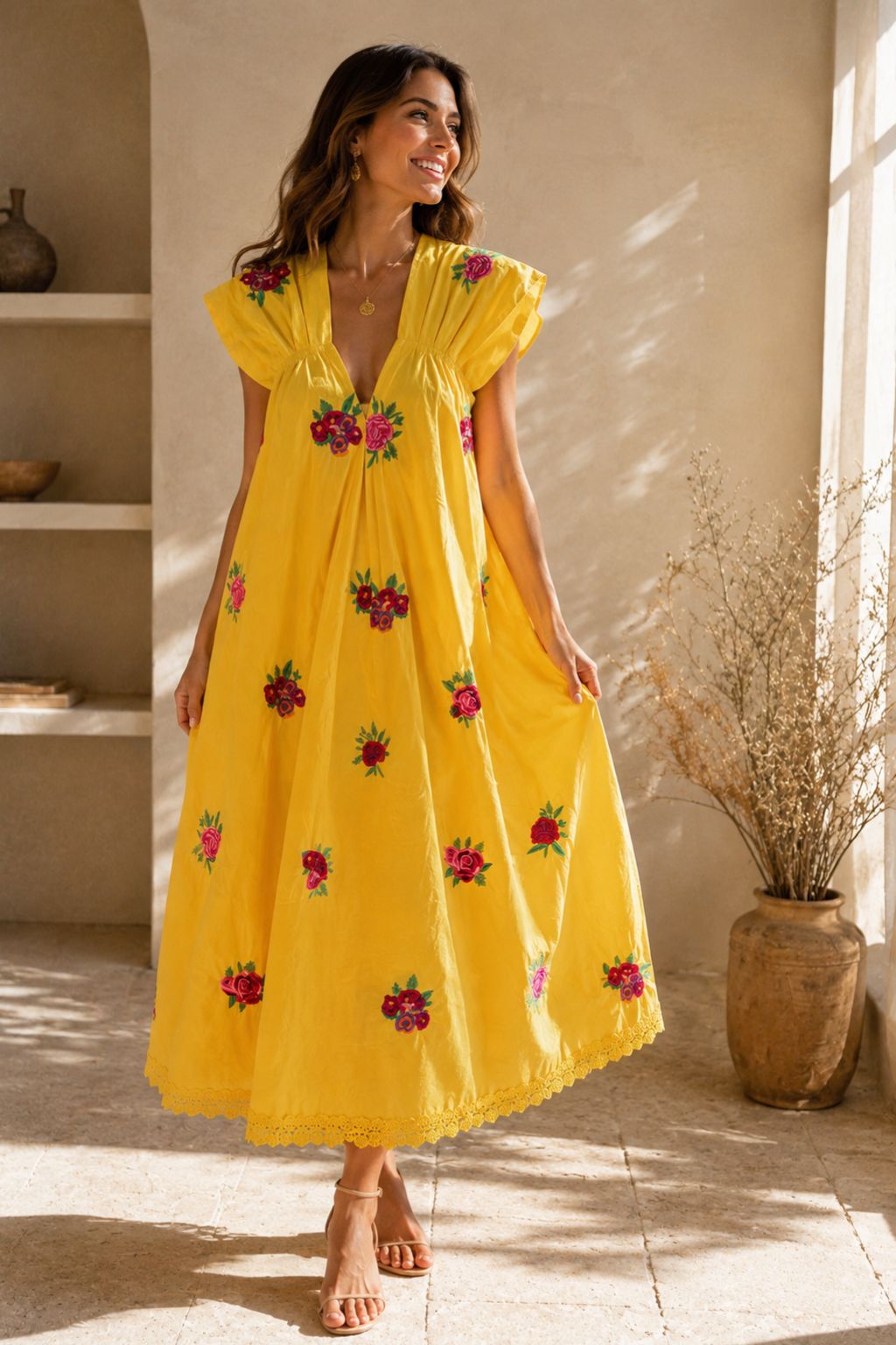 Woman wearing a yellow dress with floral embroidery in a sunlit room.