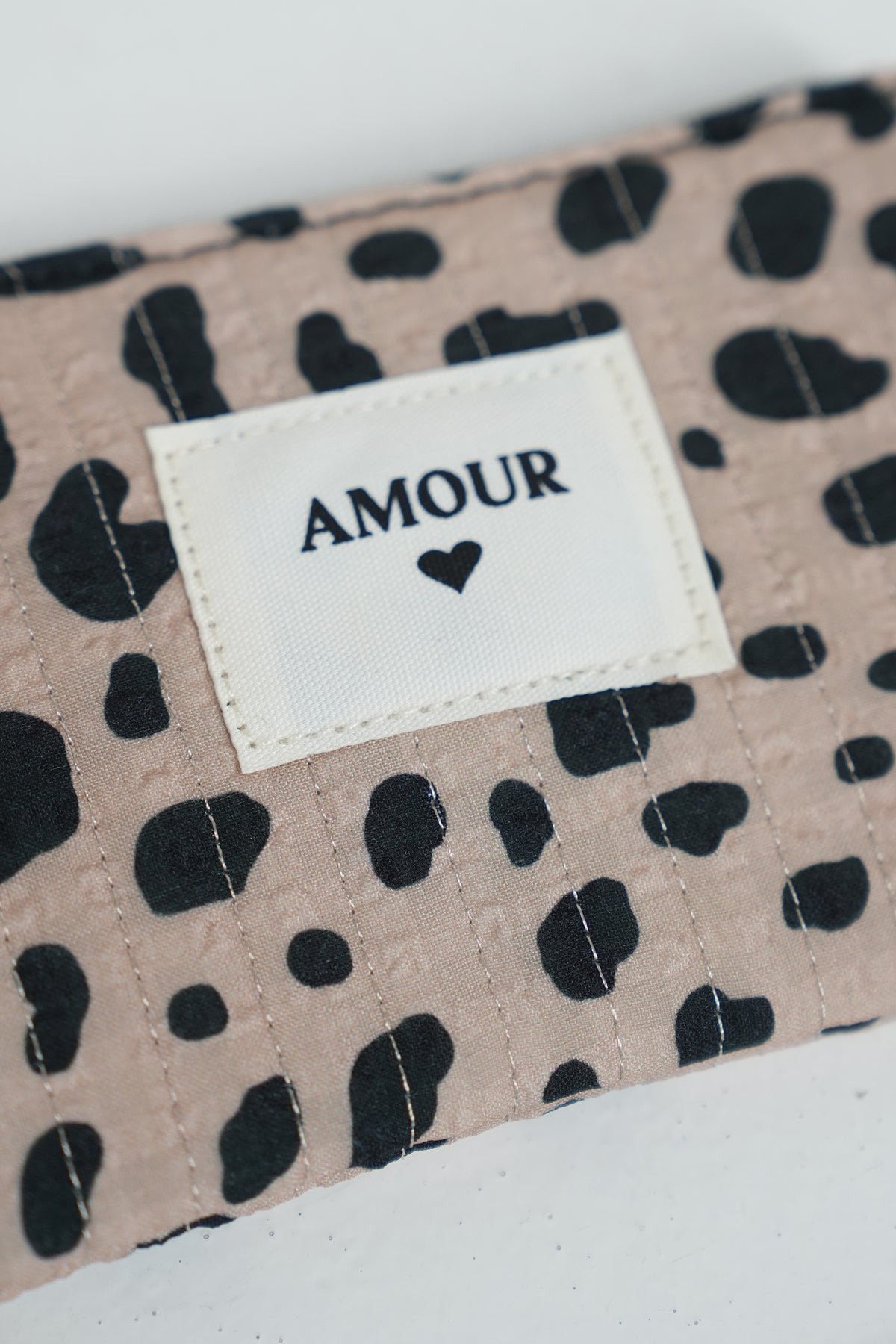 Fabric with black leopard print and 'AMOUR' label on a beige background