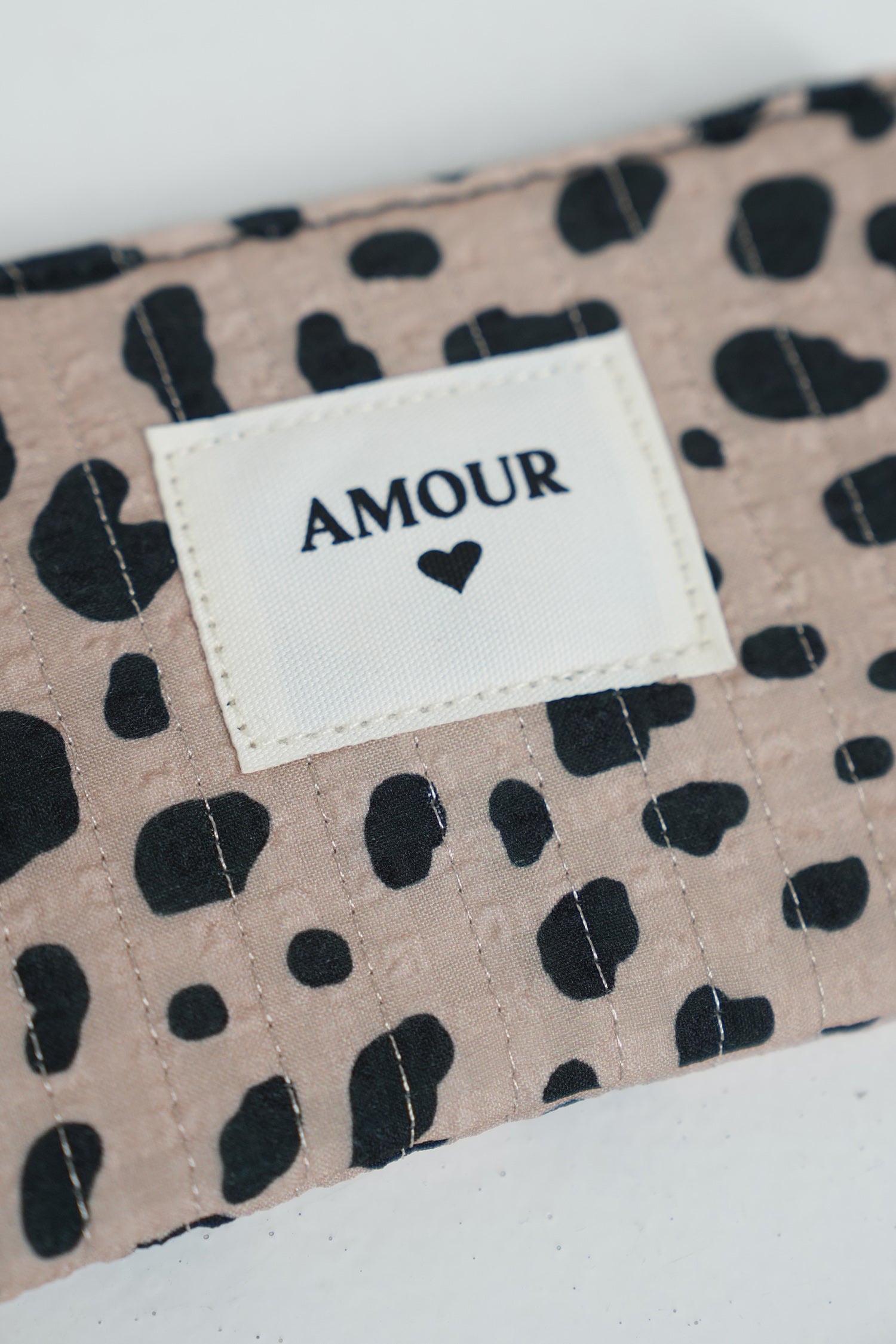 Fabric with black leopard print and 'AMOUR' label on a beige background