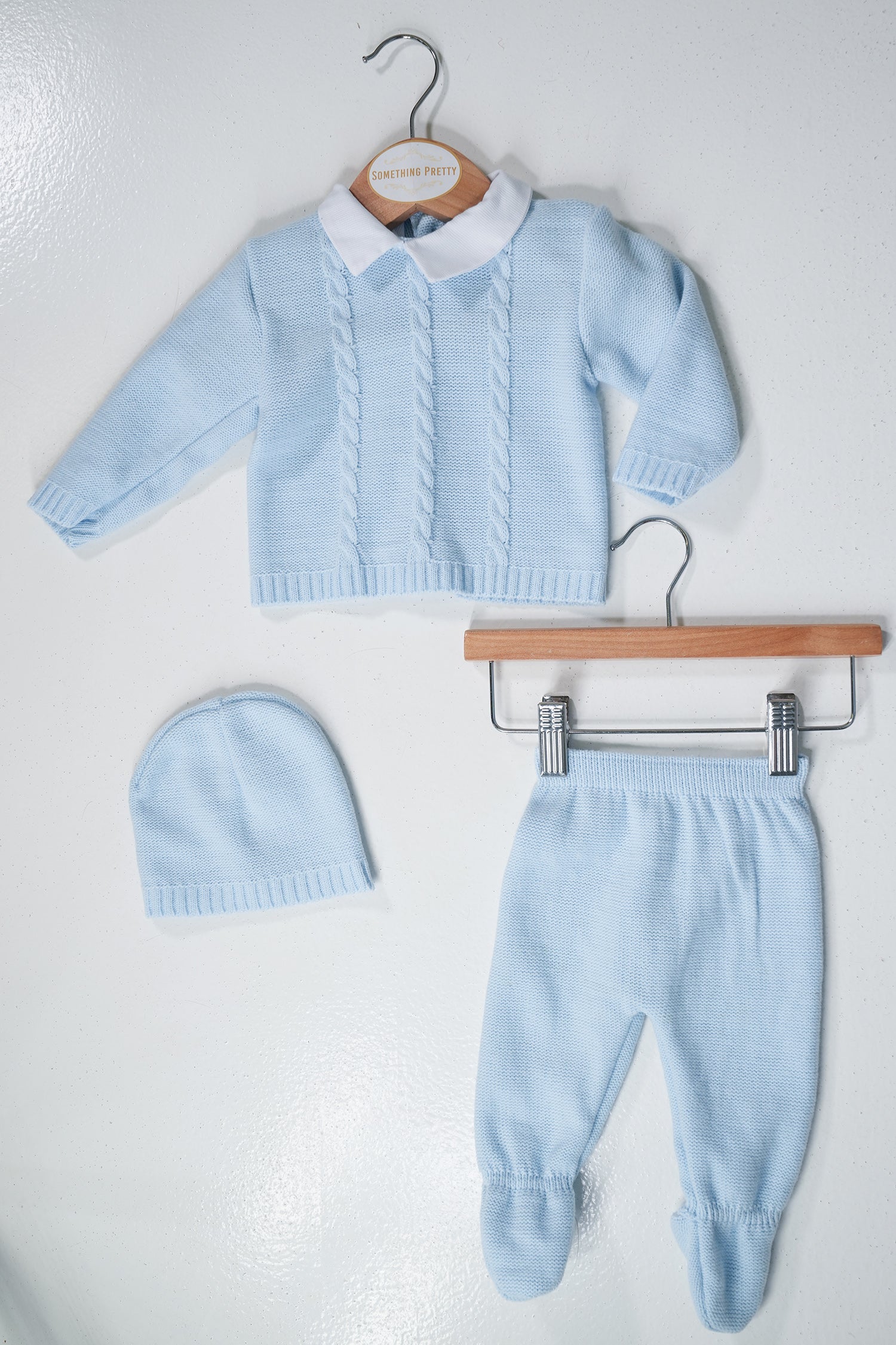 Light blue baby sweater, pants, and hat set on a white background