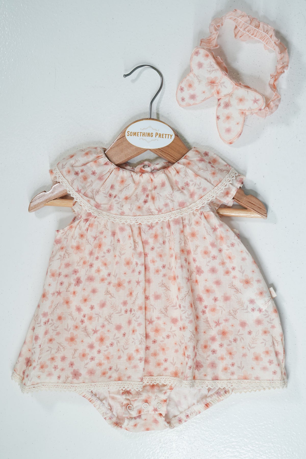 Baby romper with floral pattern and matching headband on a white background