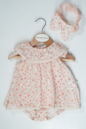 Baby romper with floral pattern and matching headband on a white background