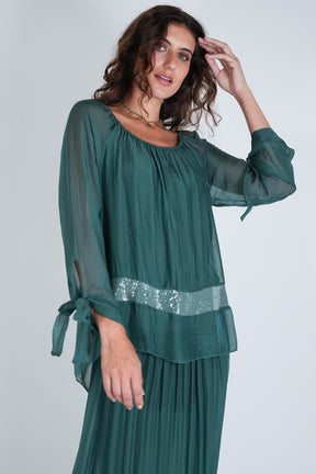 Woman wearing a green top with a sequined waistband on a white background