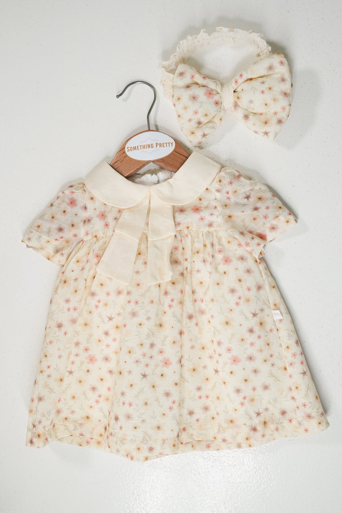 Baby dress with floral pattern and matching headband on a white background