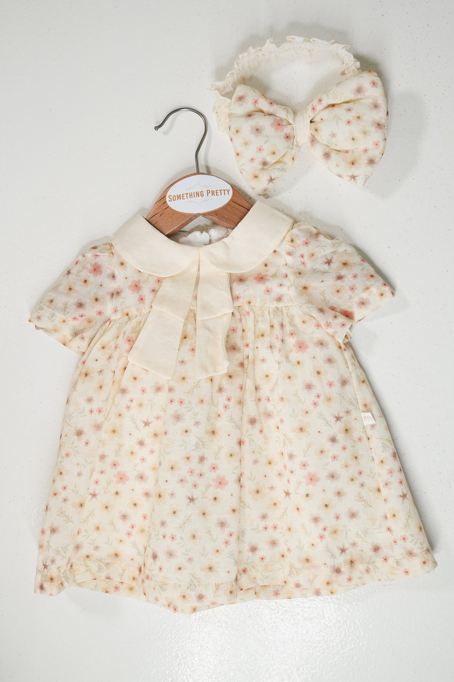 Baby dress with floral pattern and matching headband on a white background