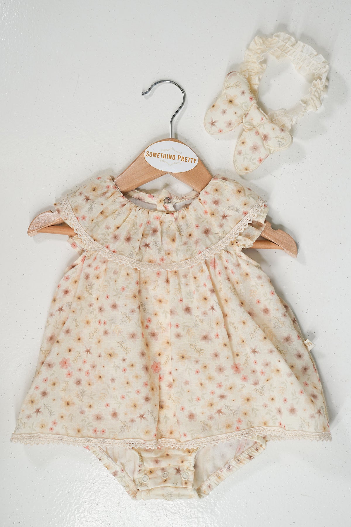 Baby romper with floral pattern and matching headband on a white background