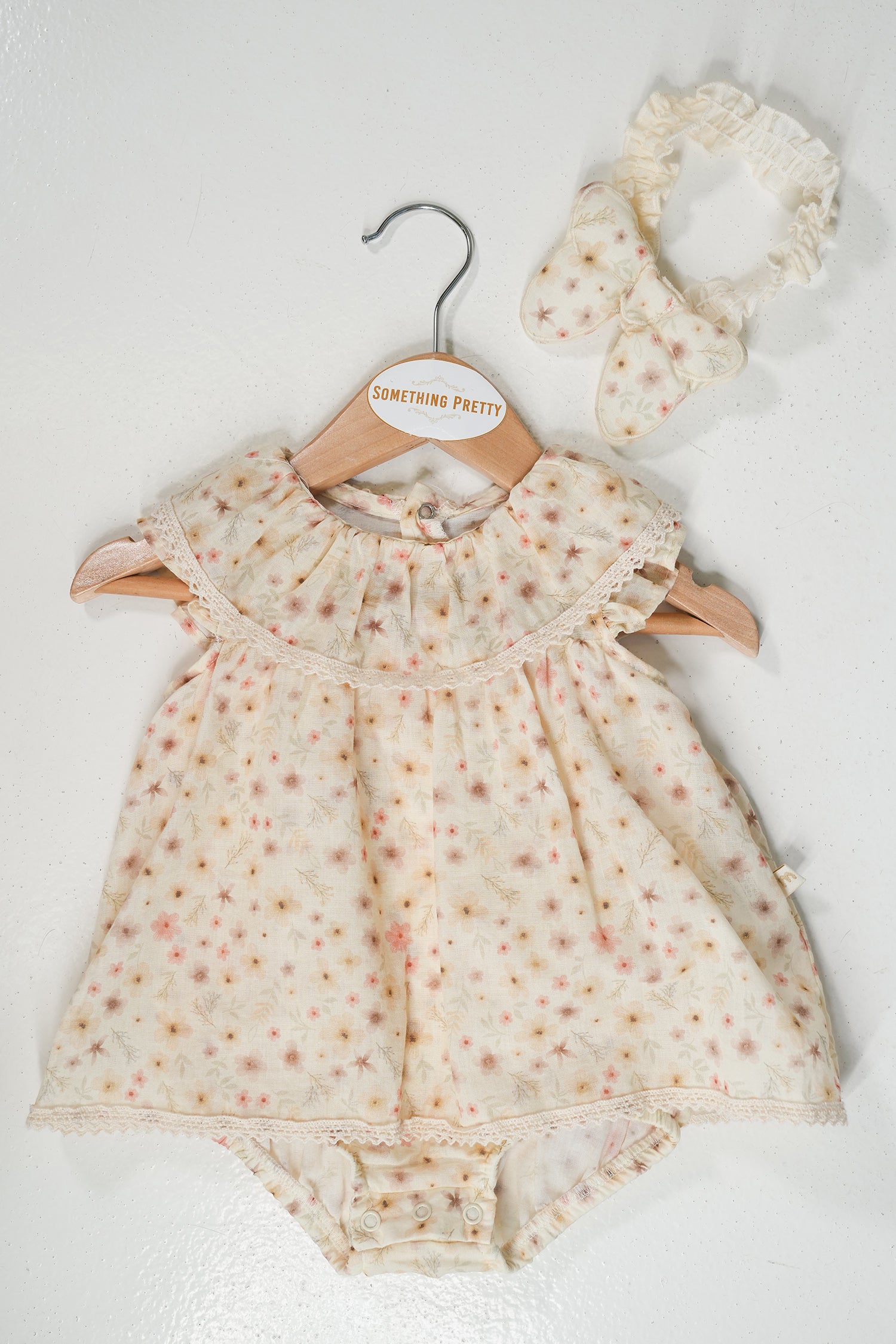 Baby romper with floral pattern and matching headband on a white background