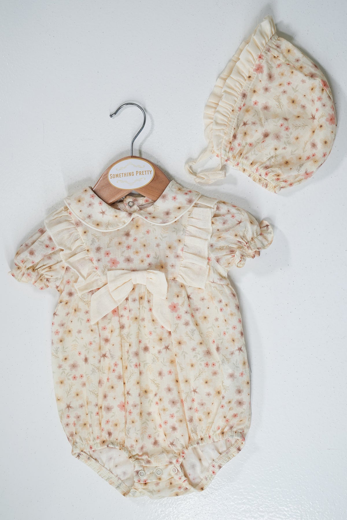 Baby romper with floral pattern and matching hat on a white background