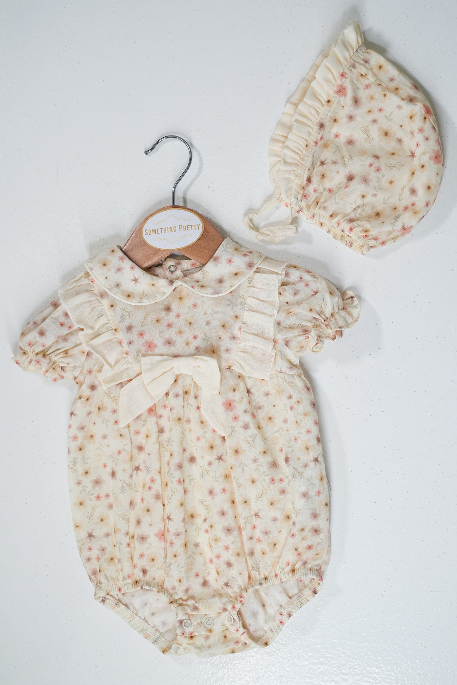 Baby romper with floral pattern and matching hat on a white background