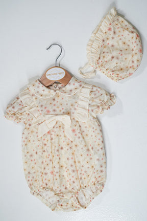 Baby romper with floral pattern and matching hat on a white background