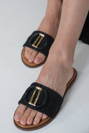 Black woven sandal with gold buckle on a white background
