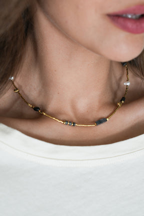 Close-up of a necklace with beads on a person wearing a white top.