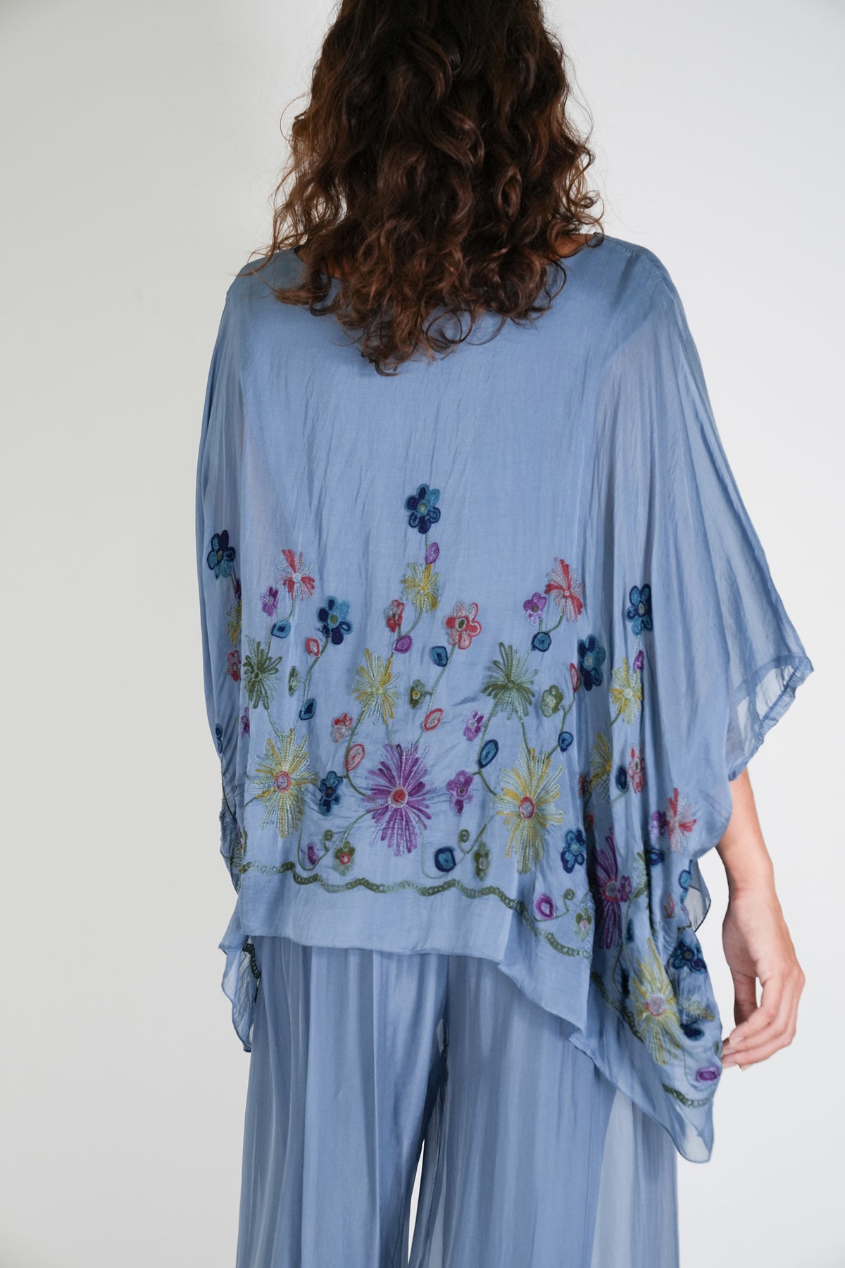 Light blue embroidered poncho worn by a person on a plain background