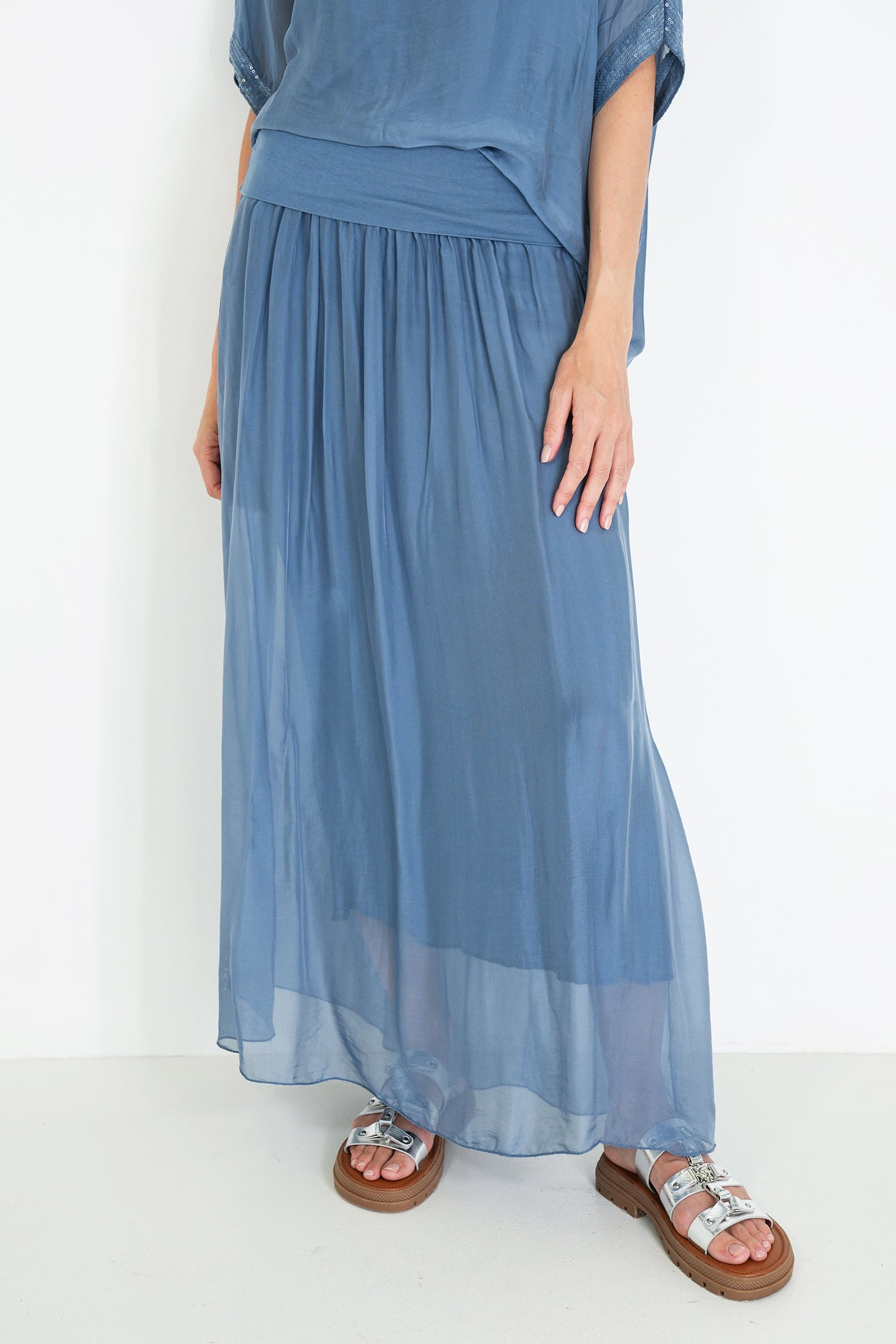 Person wearing a blue dress with sandals on a white background