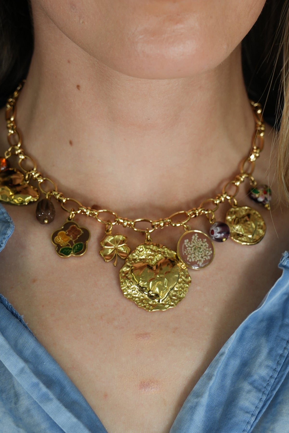 Gold necklace with various pendants worn by a person