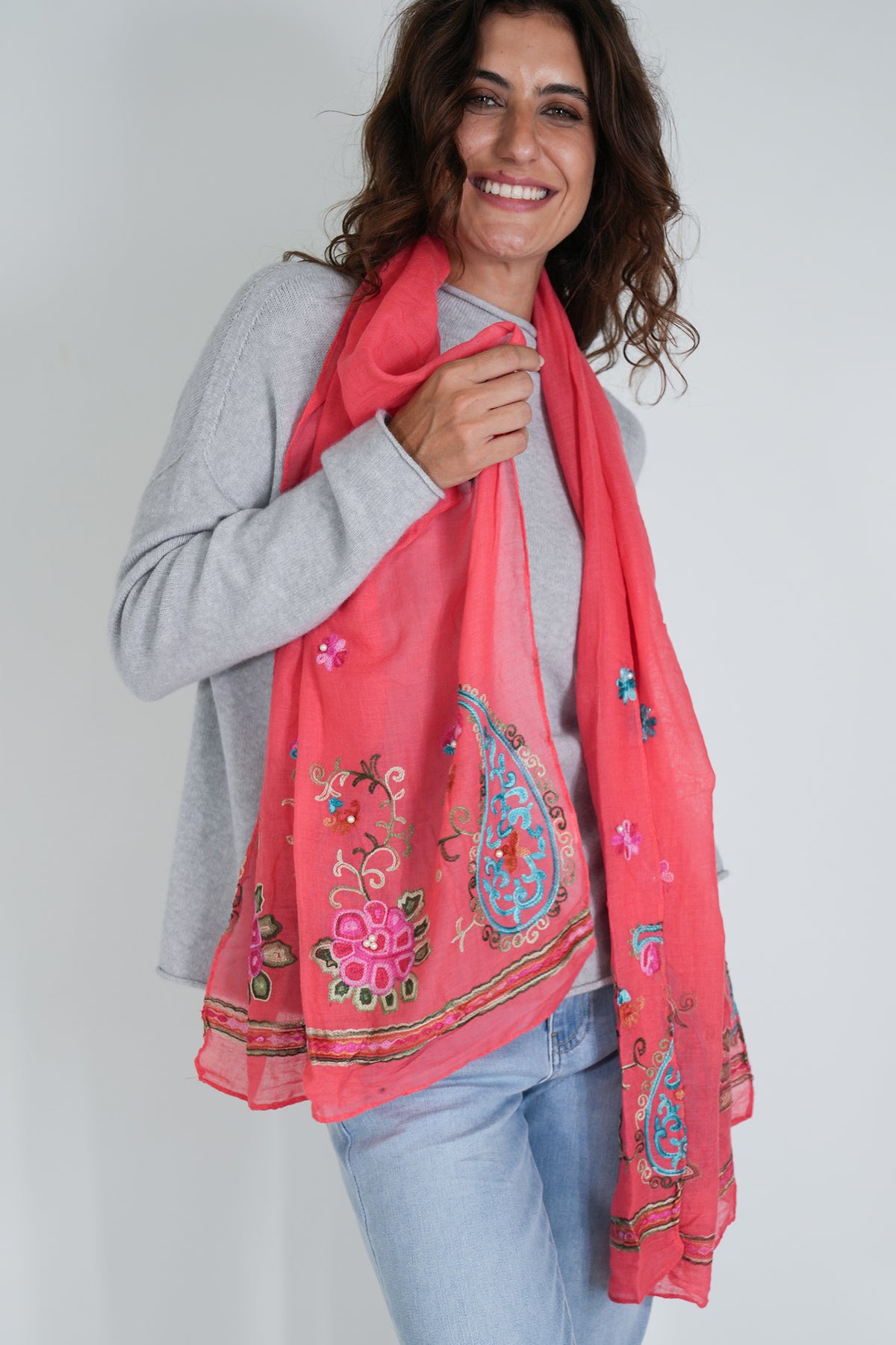 Woman wearing a pink embroidered scarf against a plain background