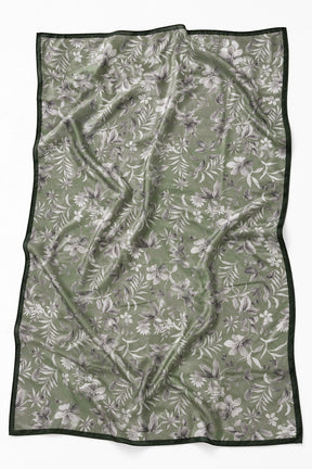 A rectangular scarf with a sage green background, featuring a white and gray floral pattern and a solid dark green border, laid flat on a white background.