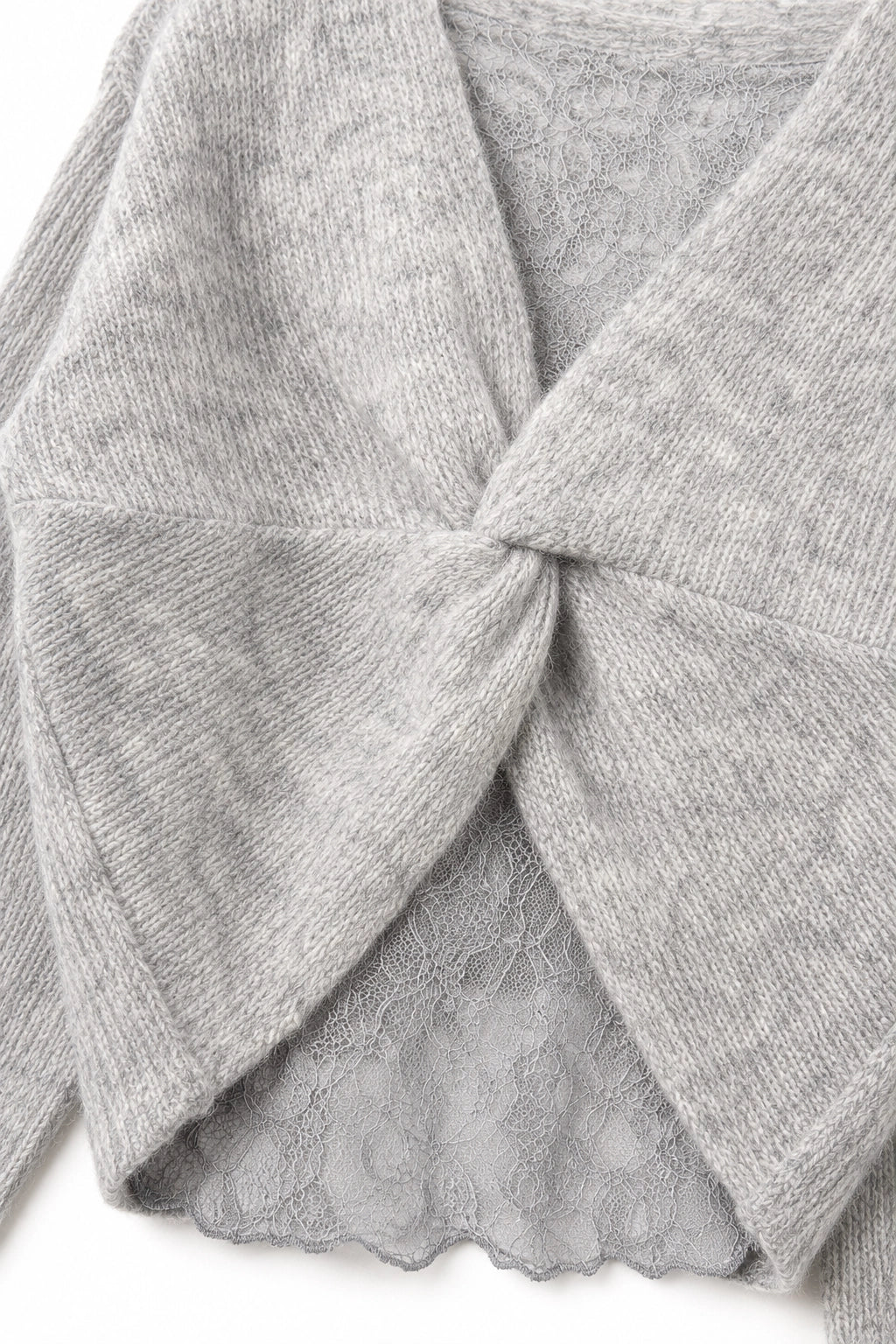 Close-up of a light gray knit cardigan with a twisted knot detail at the neckline and a scalloped lace hem, shown on a white background.