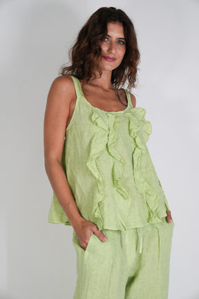 Woman wearing a light green ruffled top and pants against a white background