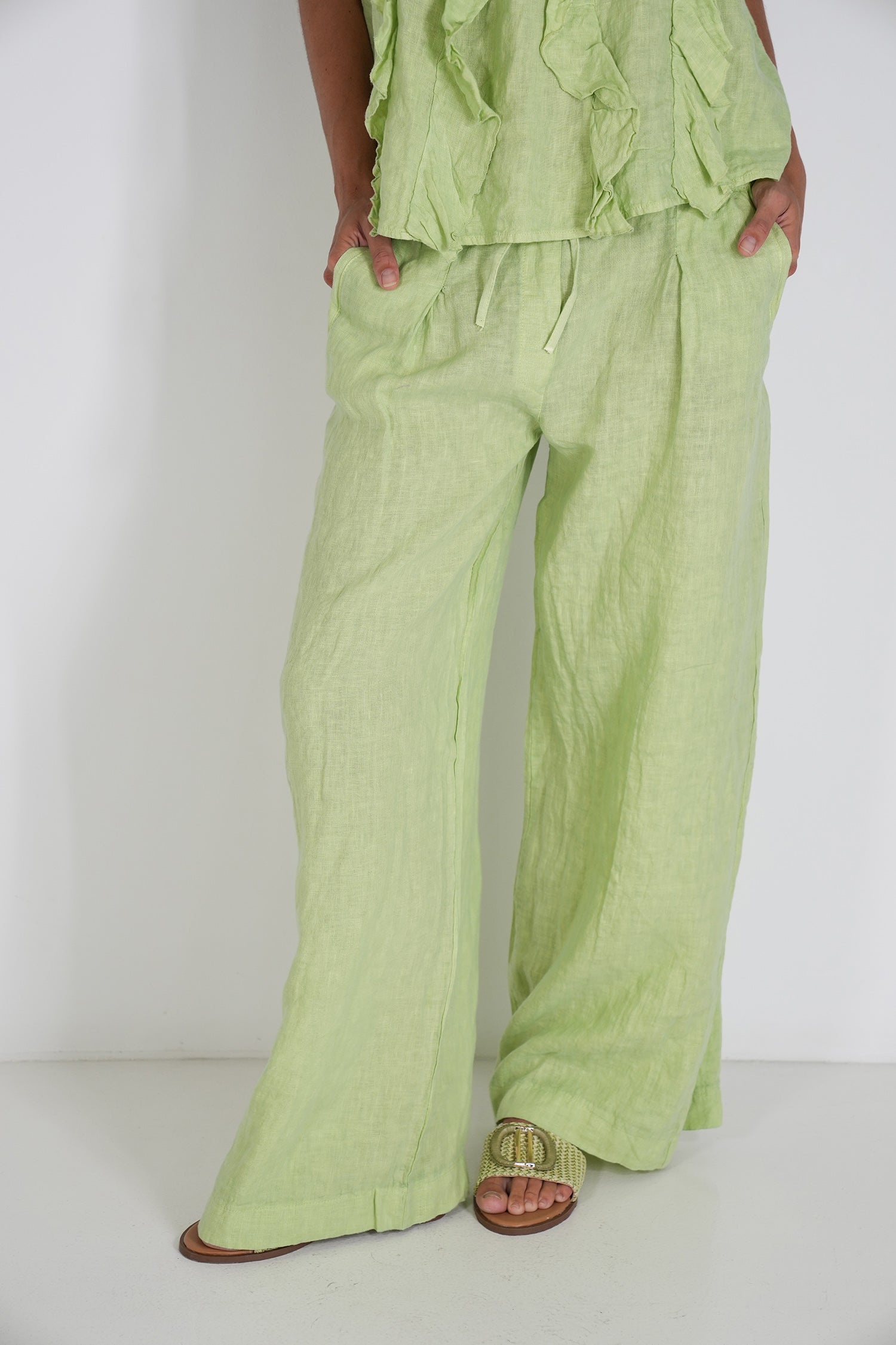 Person wearing a light green outfit with wide-leg pants on a white background