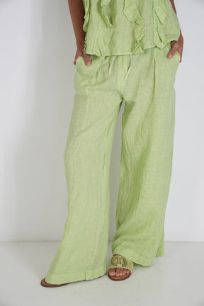 Person wearing a light green outfit with wide-leg pants on a white background
