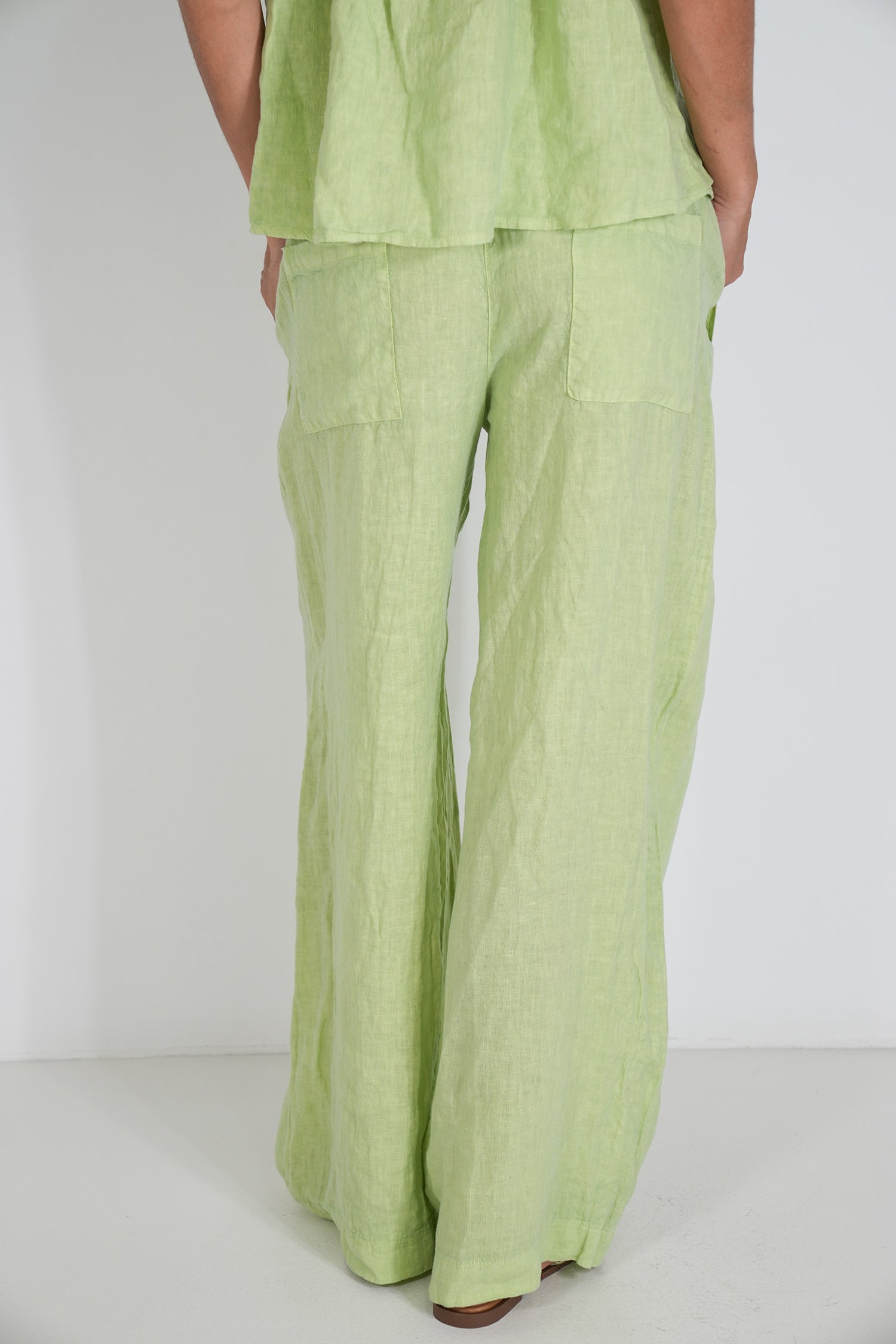 Person wearing a green outfit with wide-leg pants on a white background