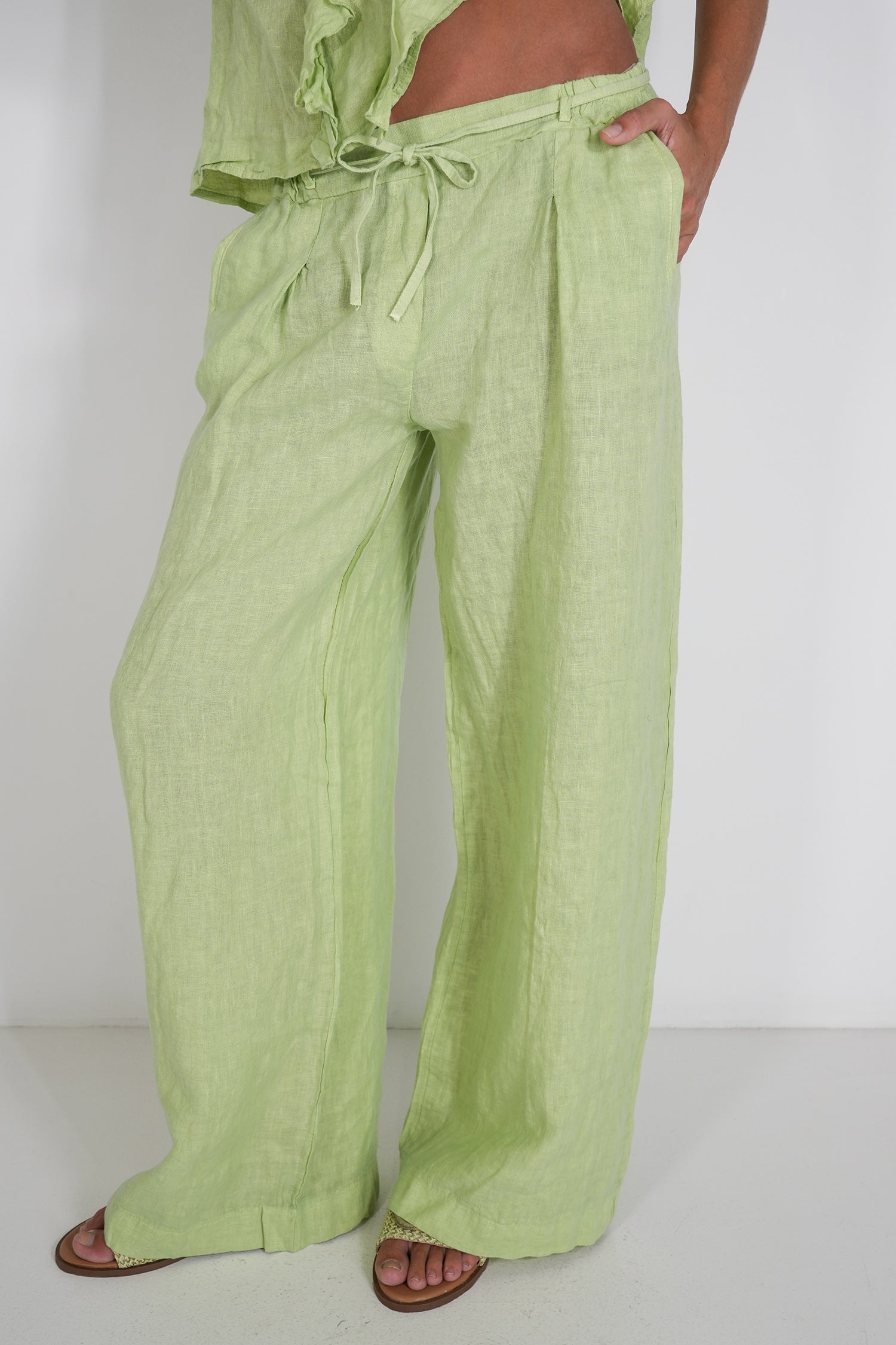Person wearing light green pants with a white background
