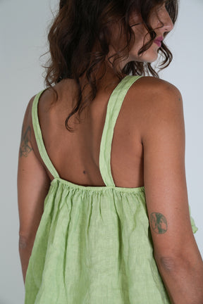 Woman wearing a light green dress with thin straps on a plain background