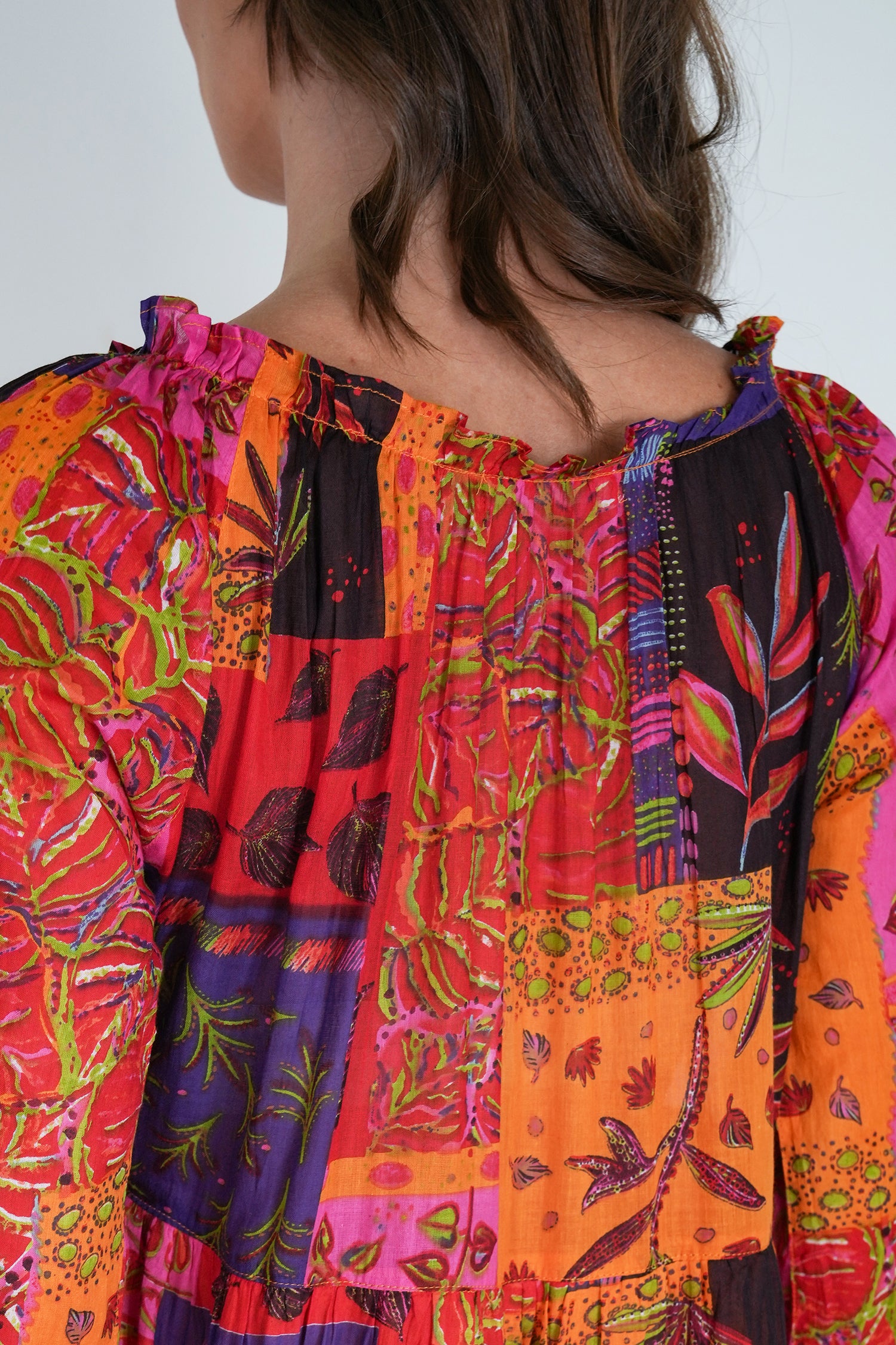 Colorful patchwork dress with floral patterns on a plain background