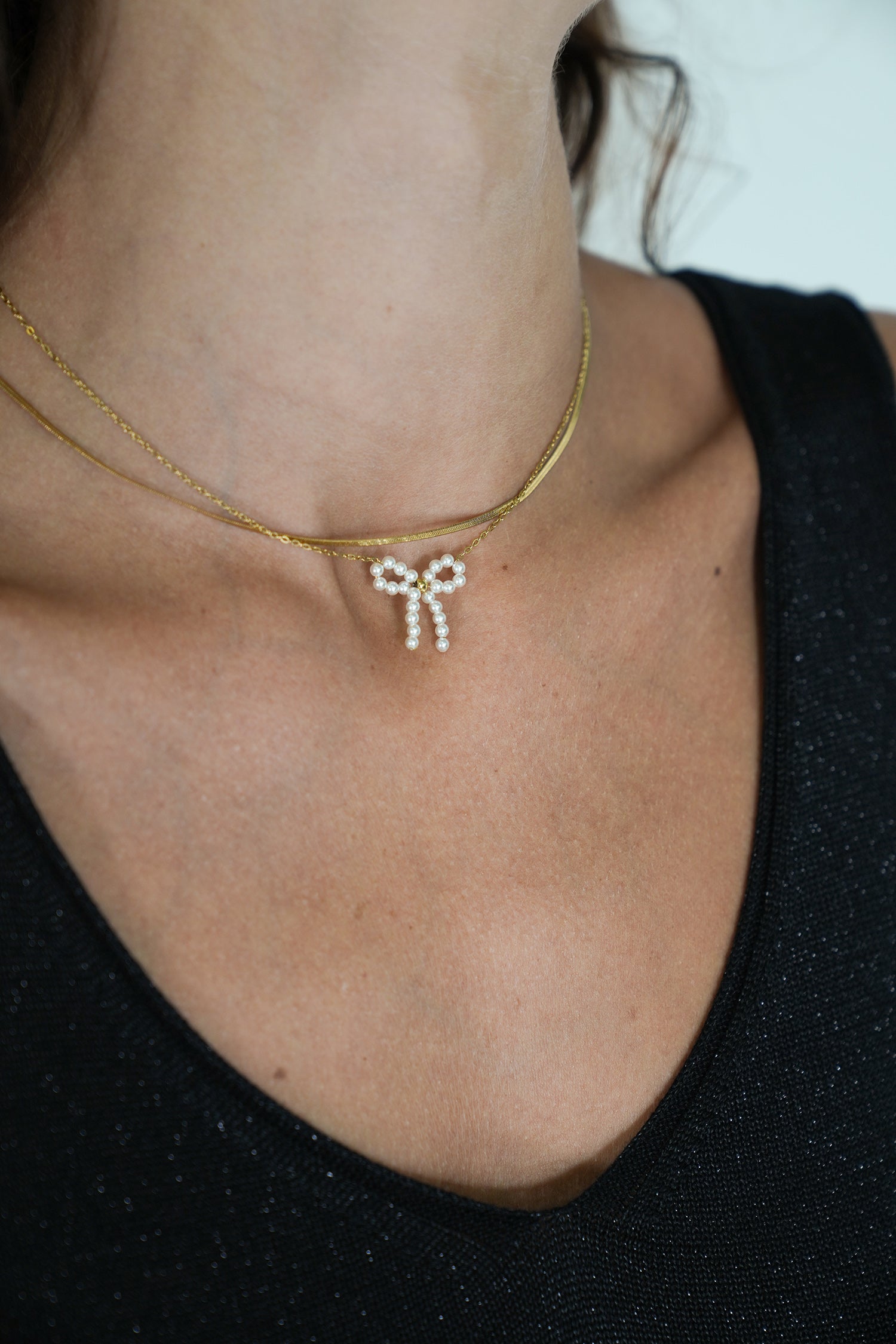 Close-up of a person wearing a delicate gold necklace with a small pendant.