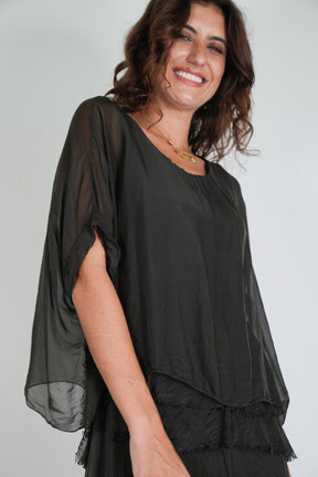 Woman wearing the Chocolate Overlay Tier Silk Dress in dark chocolate with sheer flowing sleeves and tiered ruffle detail — Something Pretty